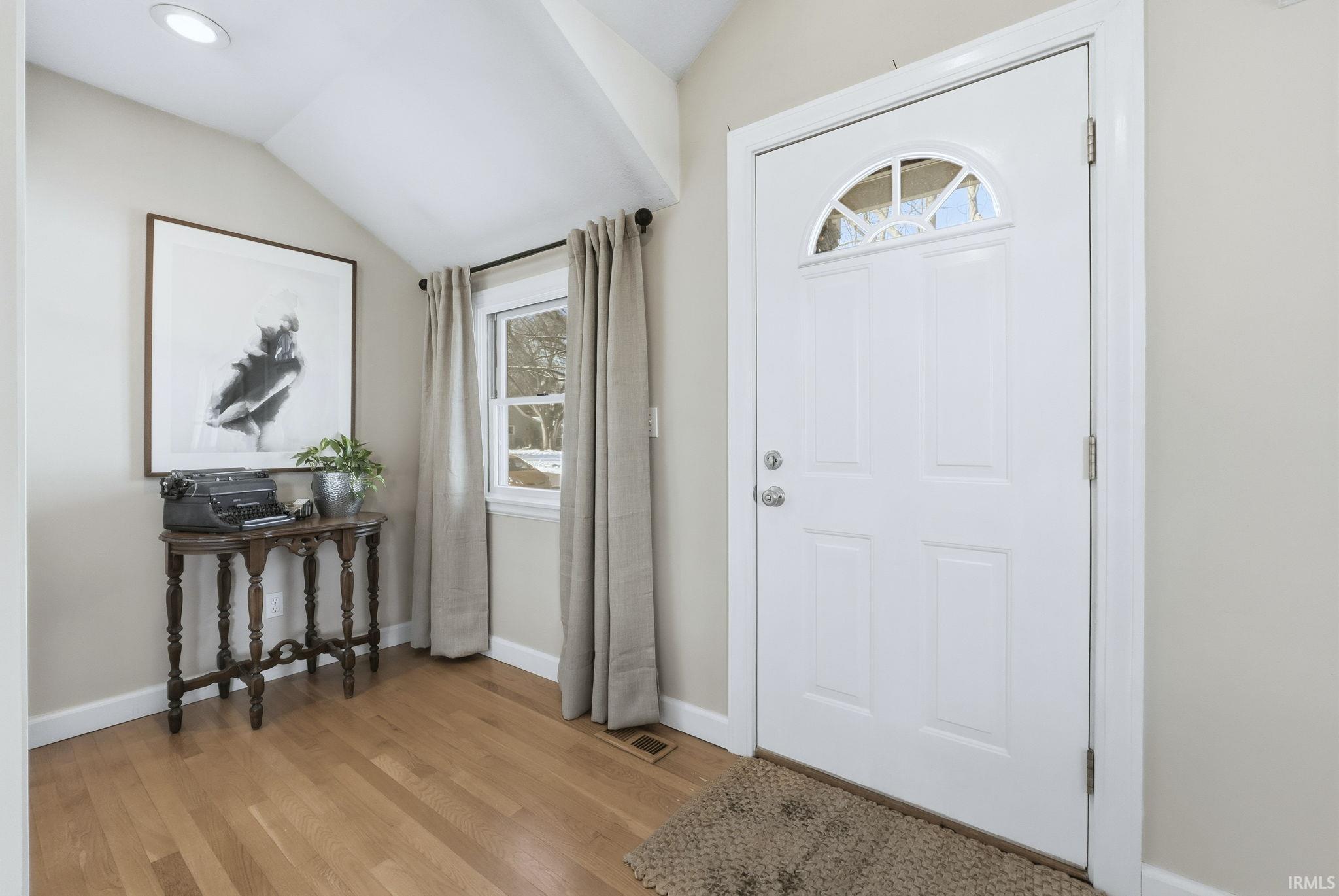 Entrance foyer with lofted ceiling and light wood-style flooring