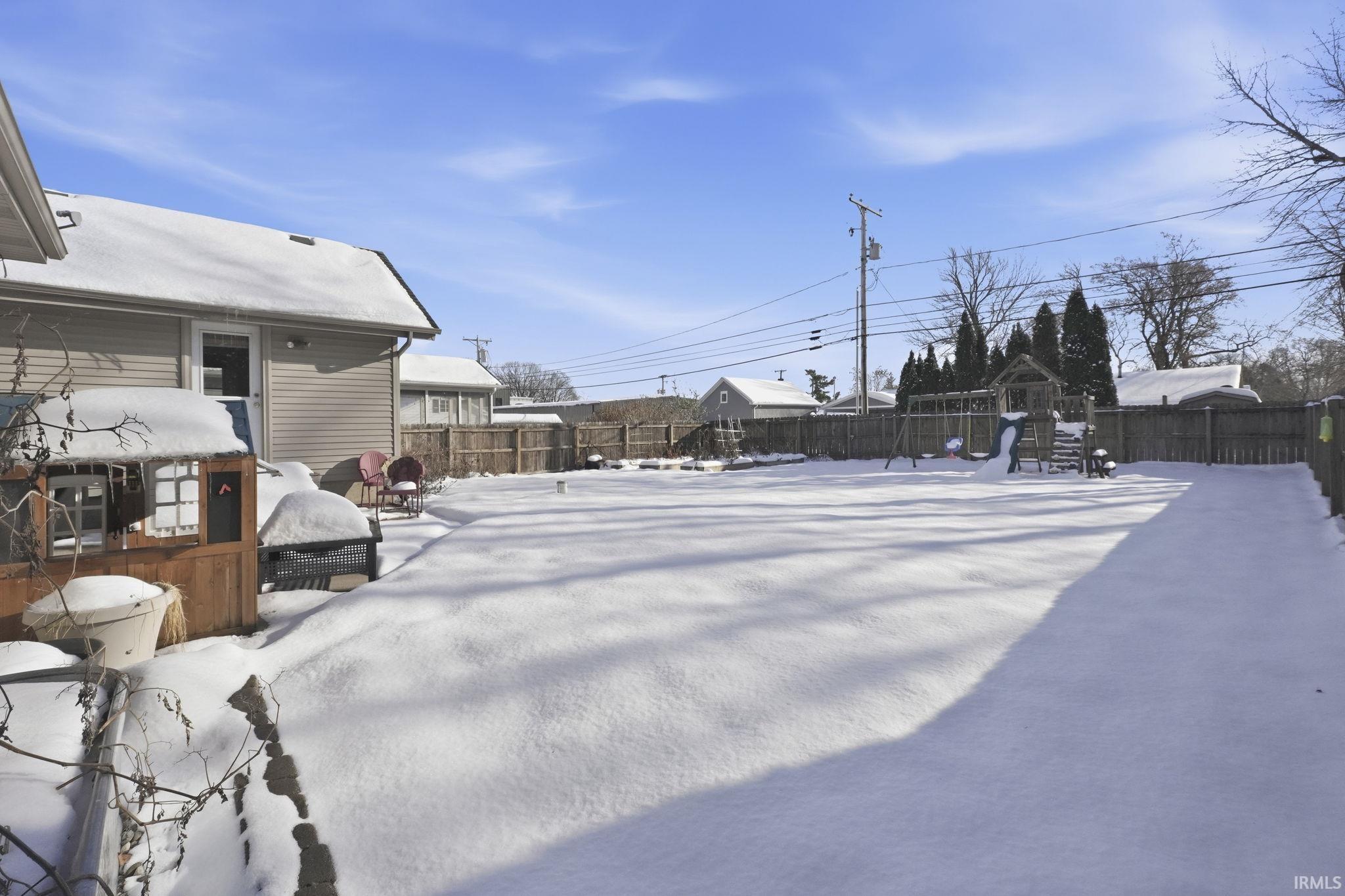 Snowy yard featuring a fenced backyard and a playground