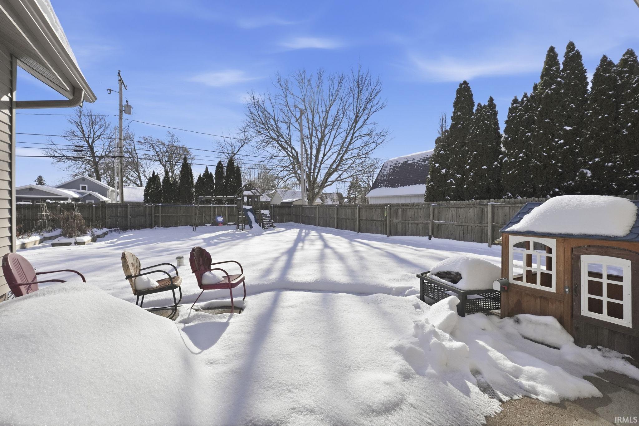 Yard layered in snow with a fenced backyard