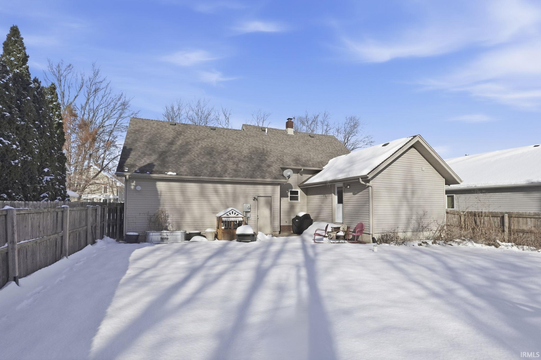 Snow covered house featuring a chimney and a patio area