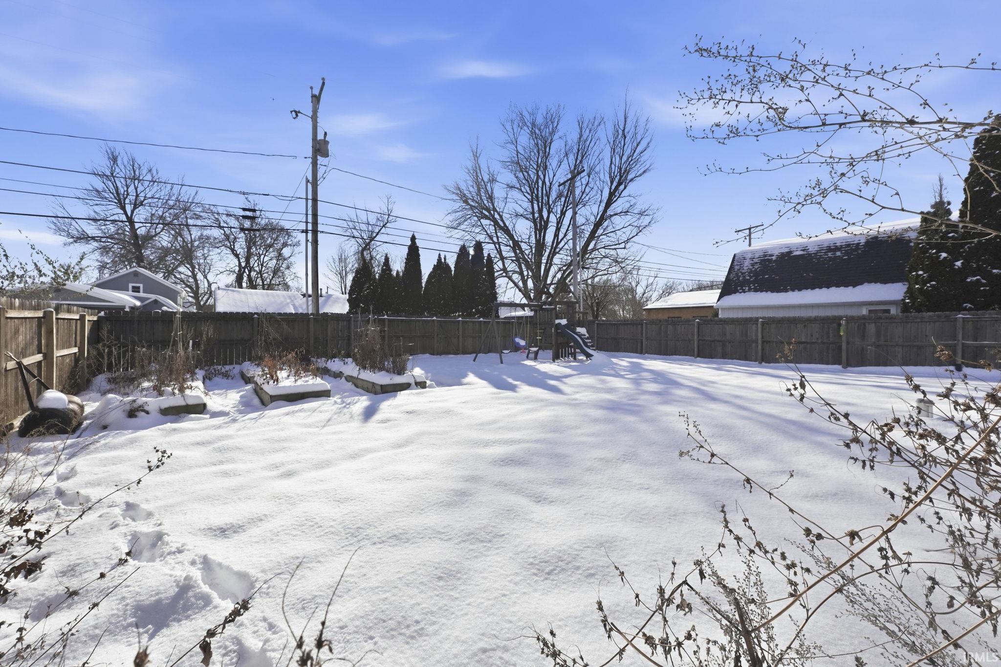 Snowy yard with a fenced backyard