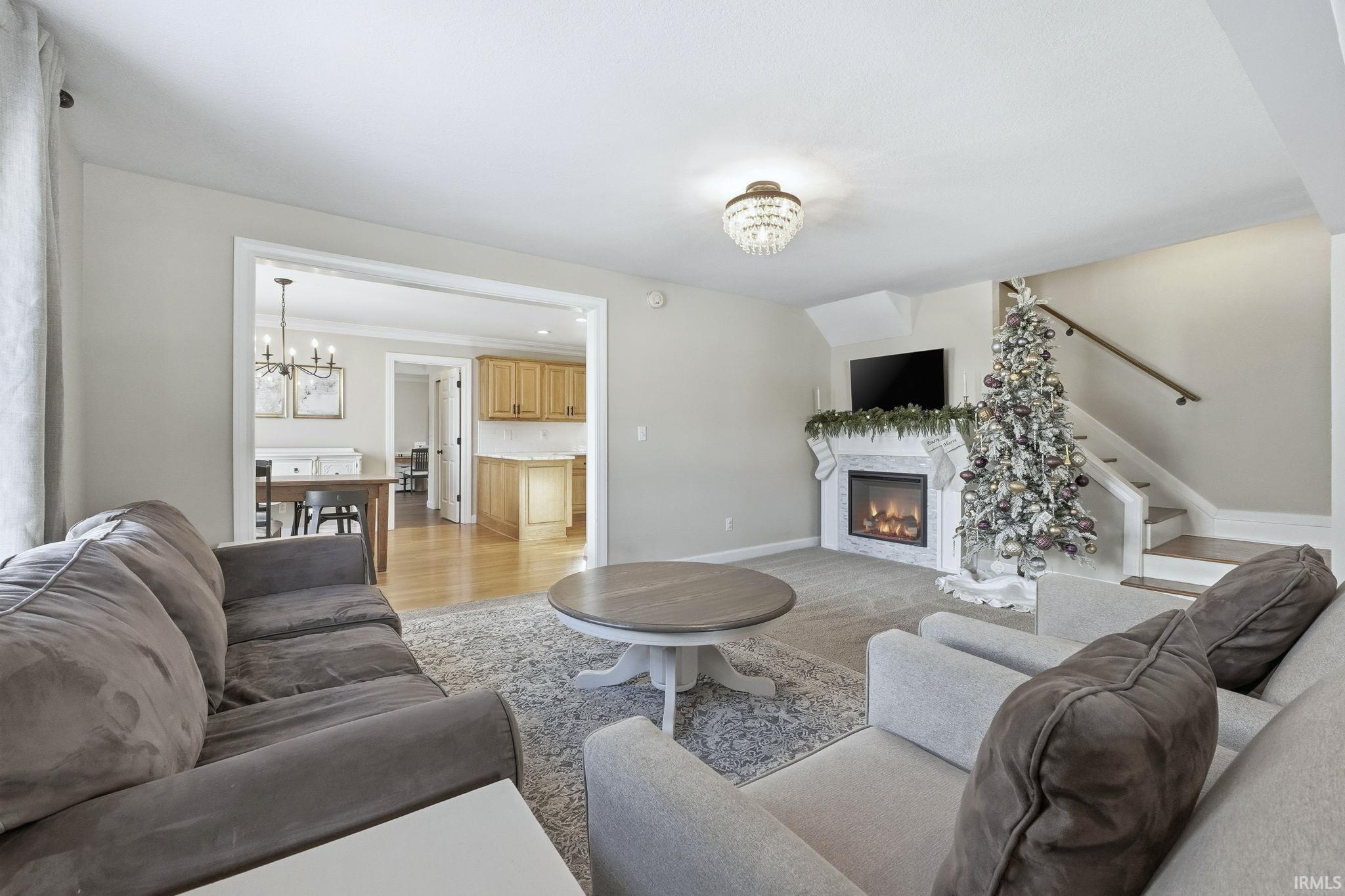 Living room featuring a chandelier, a glass covered fireplace, and light wood-style flooring