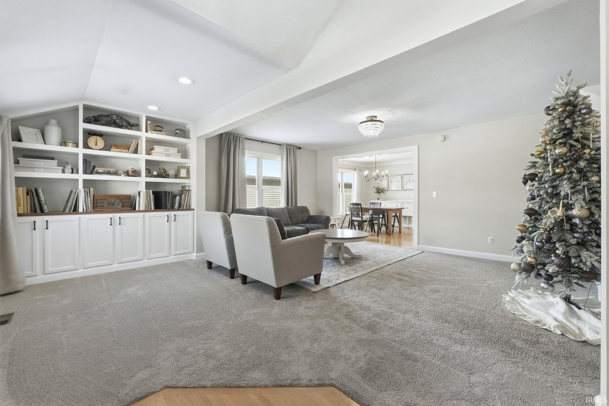 Living area with light colored carpet, a chandelier, recessed lighting, and lofted ceiling