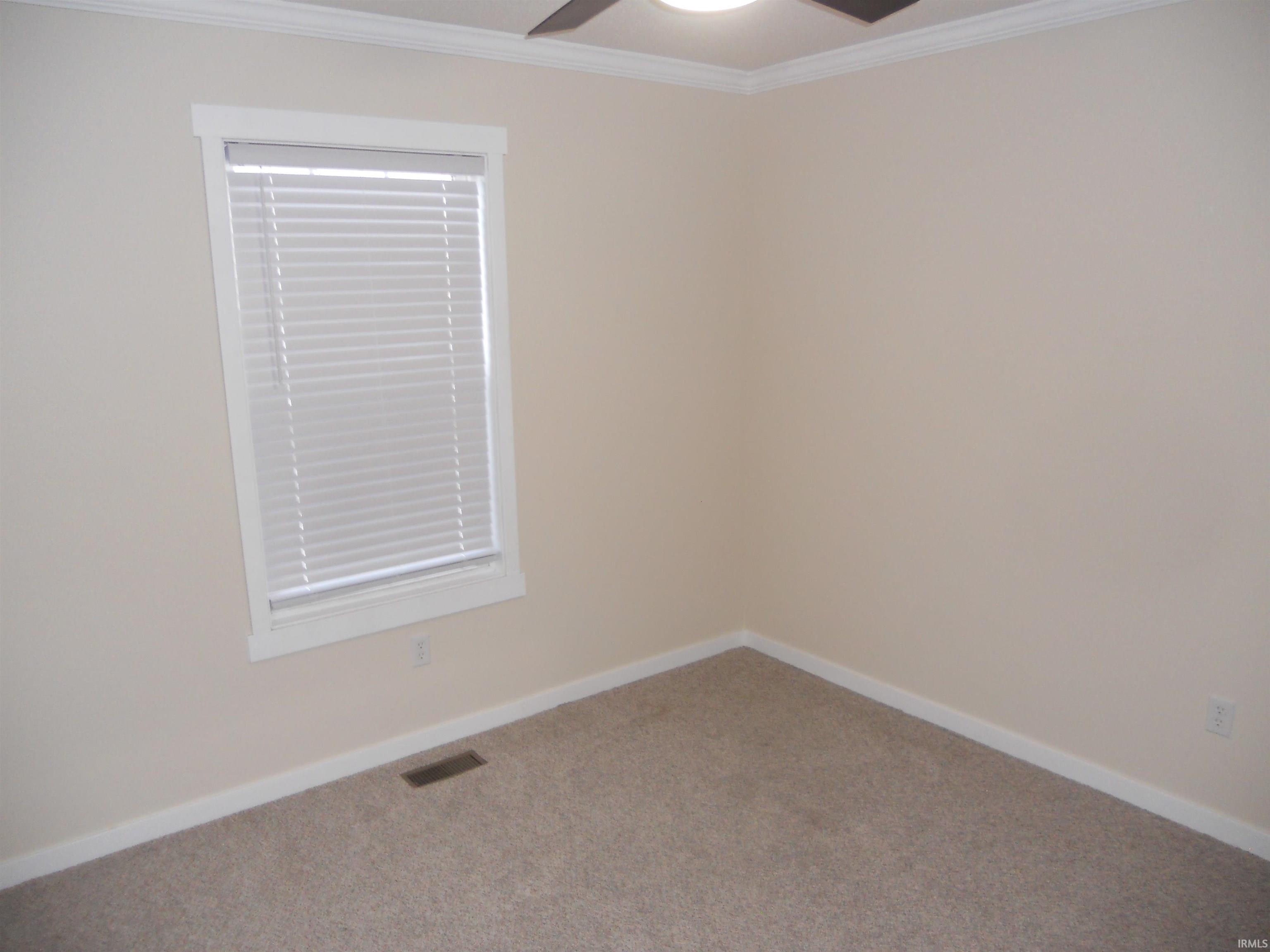 Carpeted empty room with ornamental molding and a ceiling fan