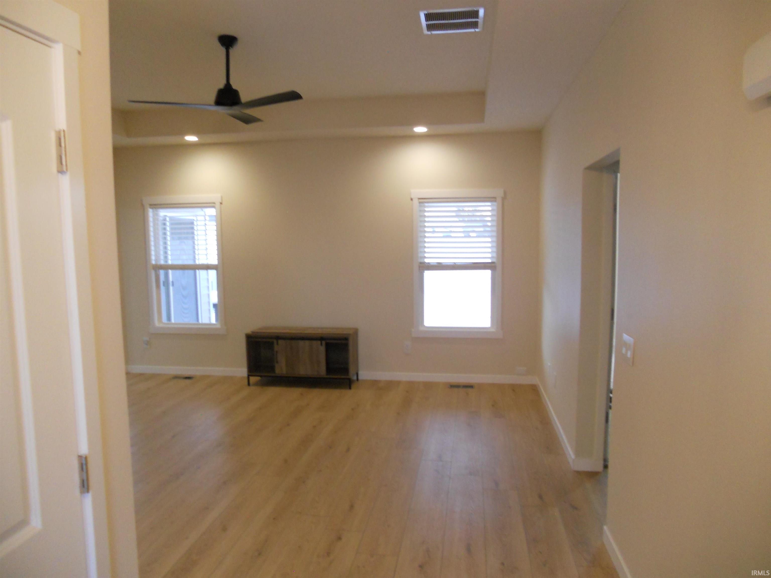Unfurnished room featuring light wood finished floors, a tray ceiling, ceiling fan, and recessed lighting