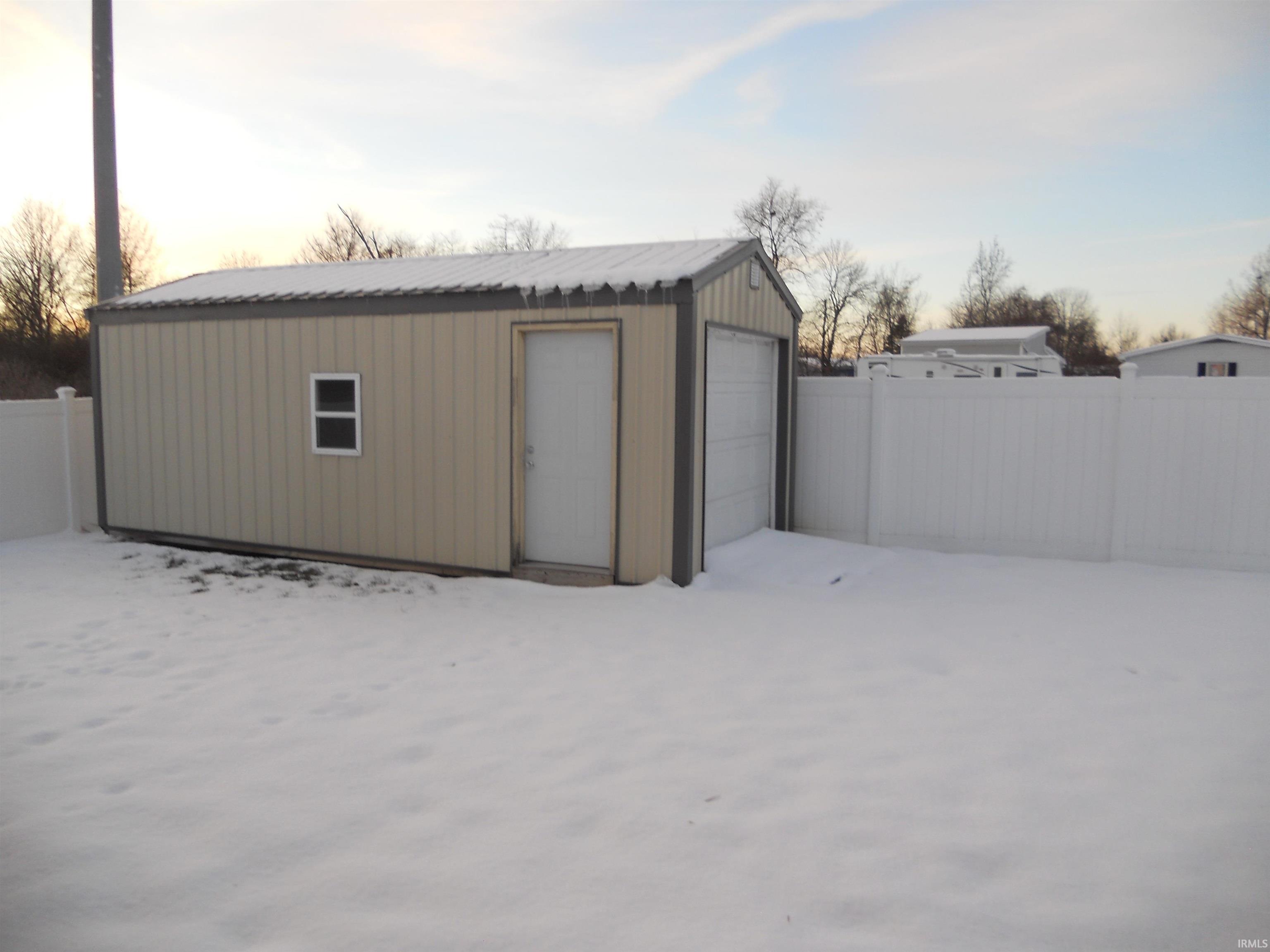 Snow covered garage with a detached garage