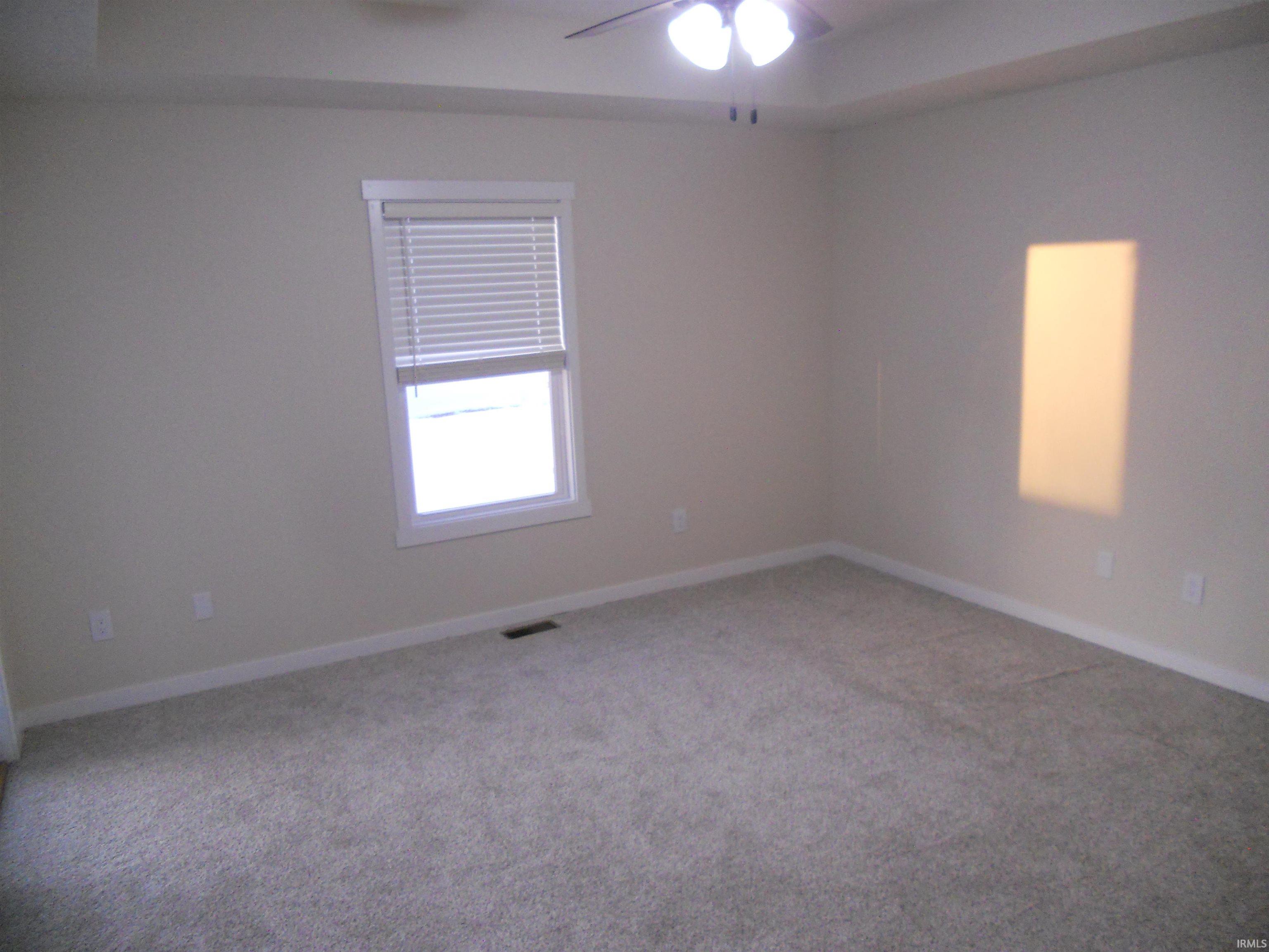 Carpeted spare room featuring baseboards and ceiling fan