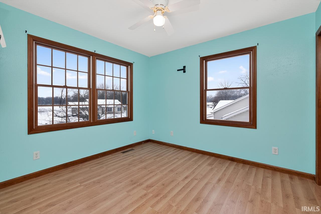 Empty room with light wood-style floors, healthy amount of natural light, and ceiling fan