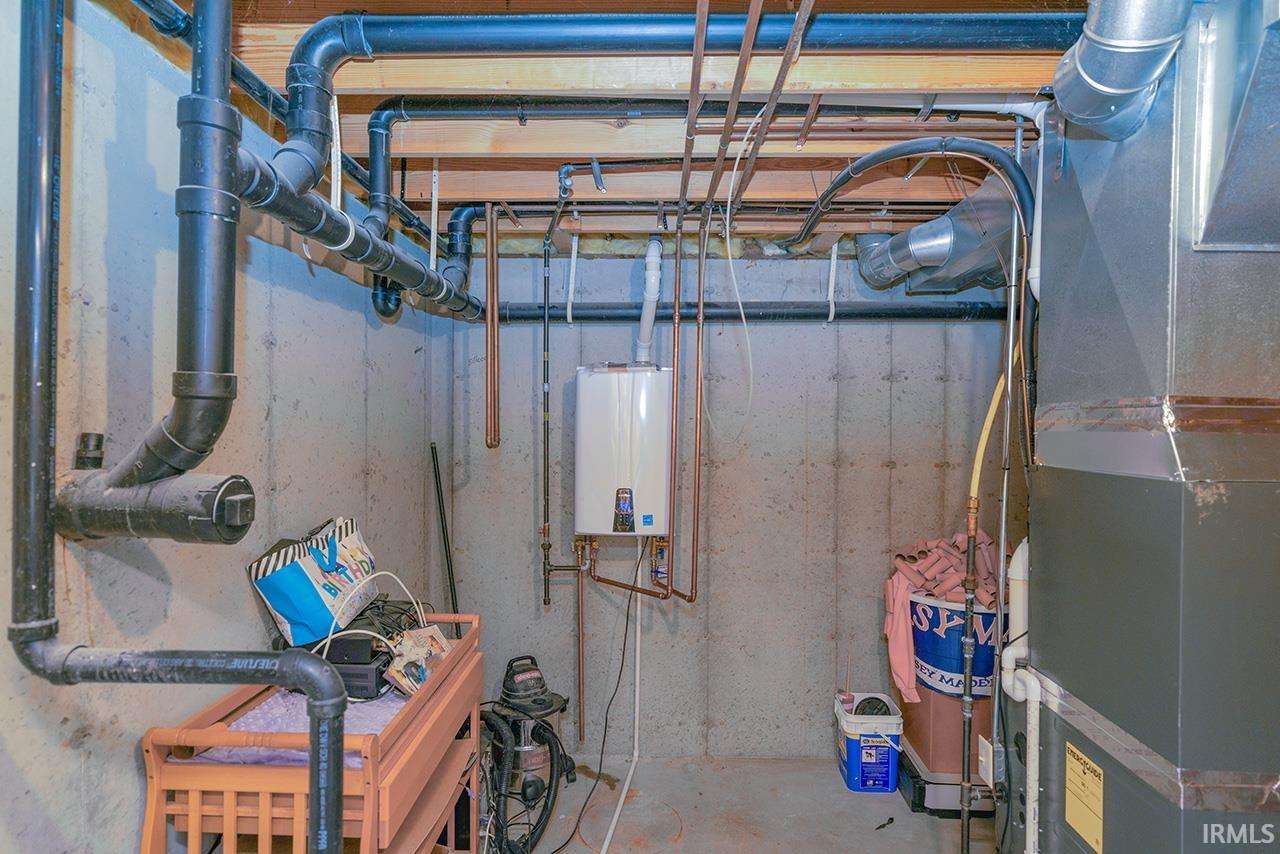 Unfinished basement featuring heating unit and tankless water heater