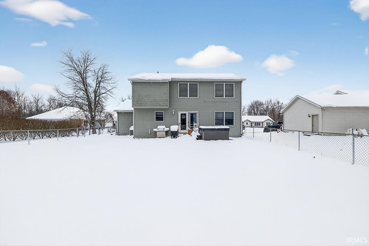 Snow covered property with a hot tub, a fenced backyard, a patio, and french doors