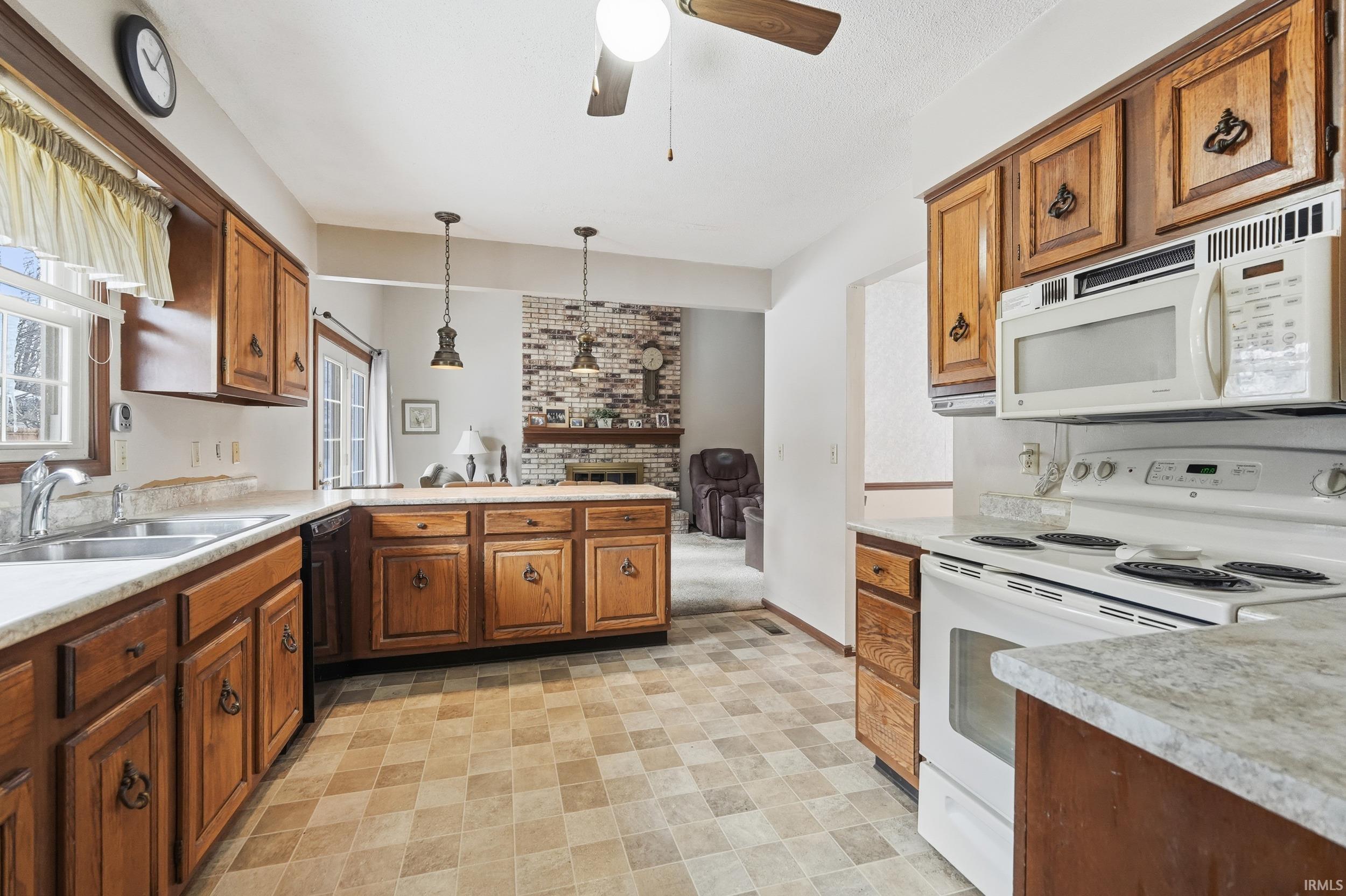 Kitchen with white appliances, light countertops, a peninsula, pendant lighting, and ceiling fan