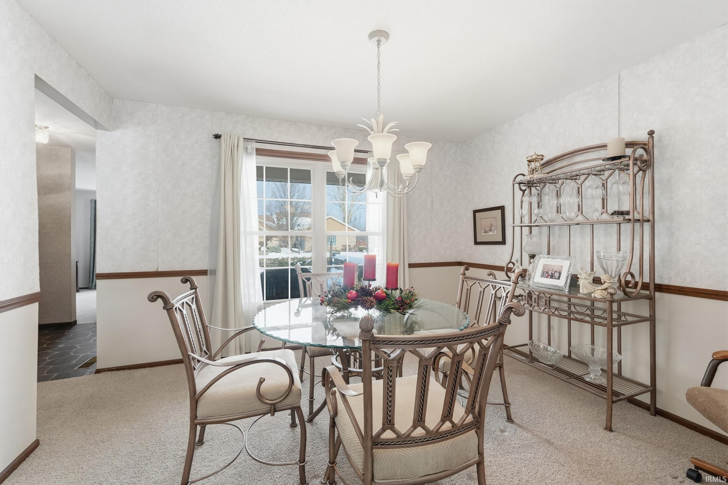 Dining space with light colored carpet and a chandelier