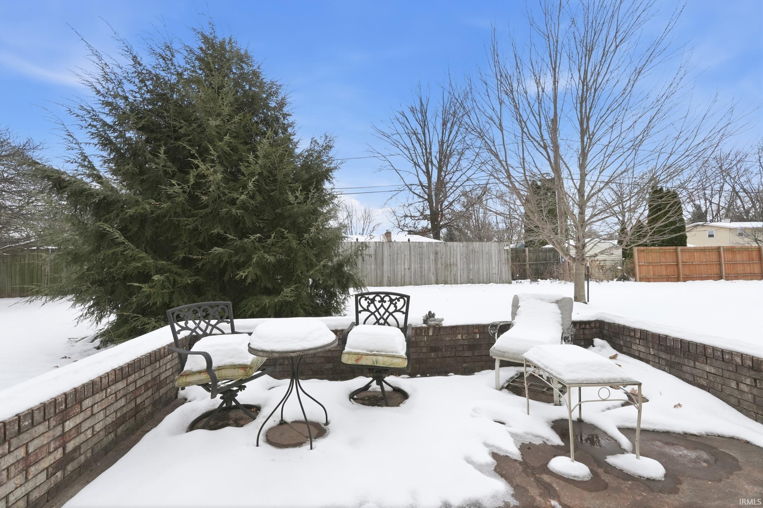 Snow covered patio with a fenced backyard