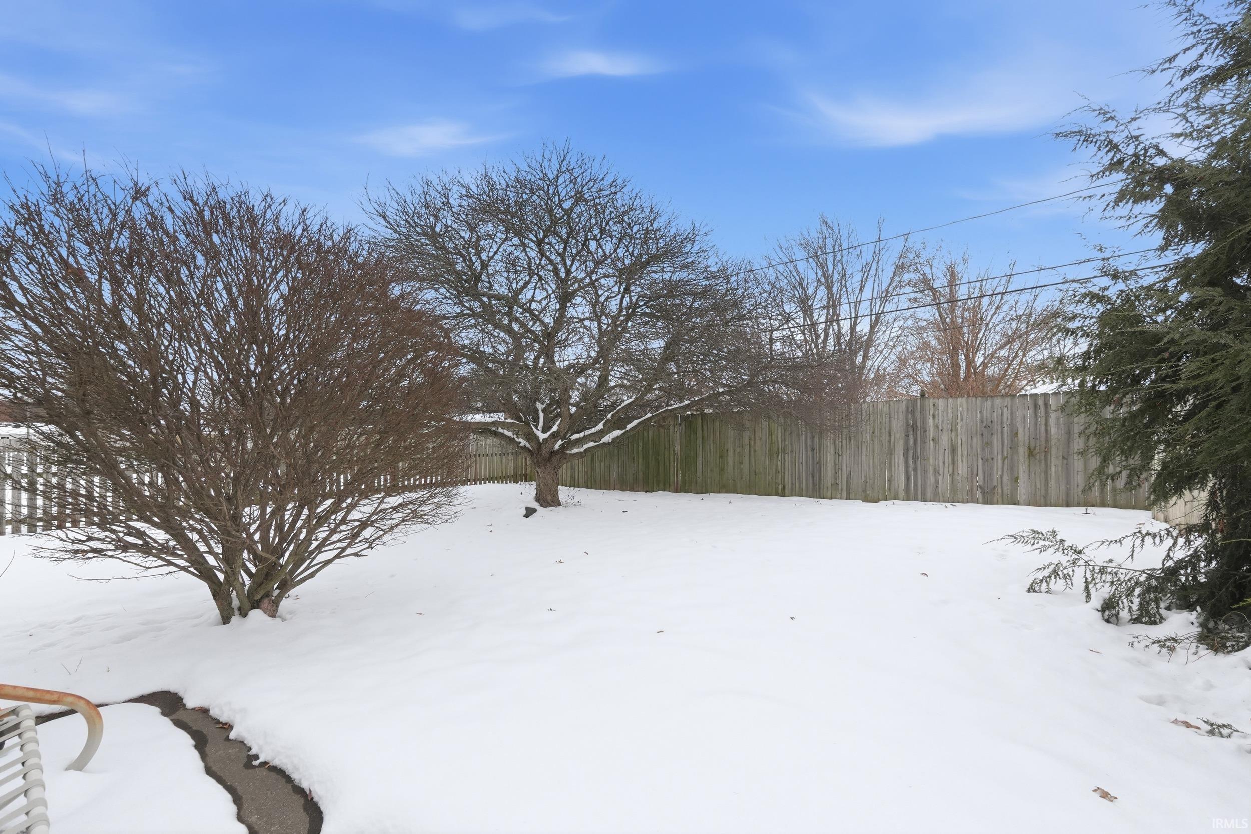 Yard layered in snow featuring a fenced backyard