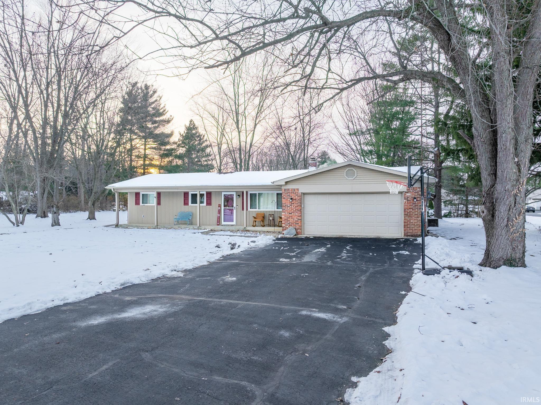 Ranch-style house with a garage, asphalt driveway, and brick siding