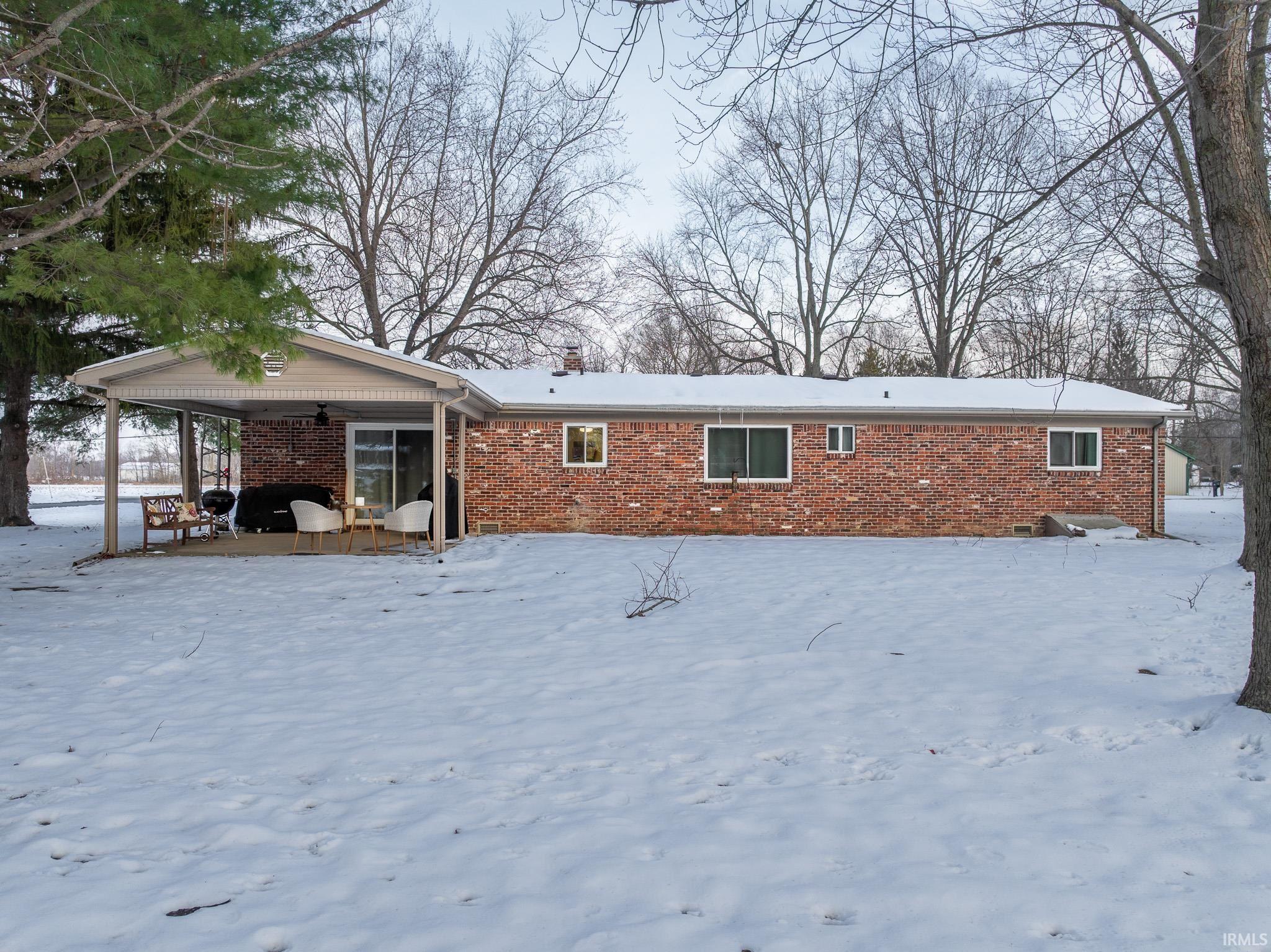 Snow covered property with brick siding and a patio