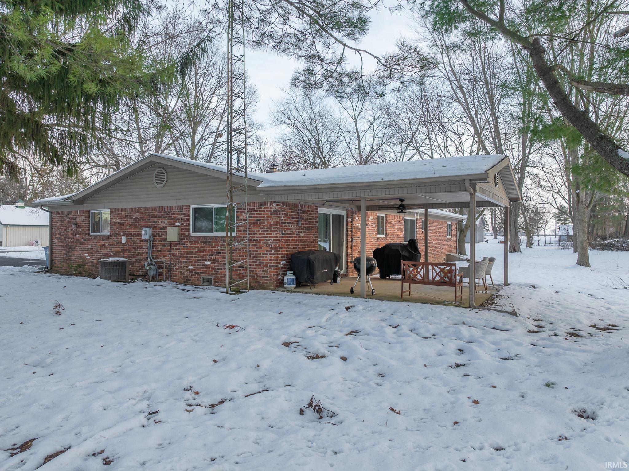 Snow covered rear of property featuring brick siding, a patio area, and ceiling fan