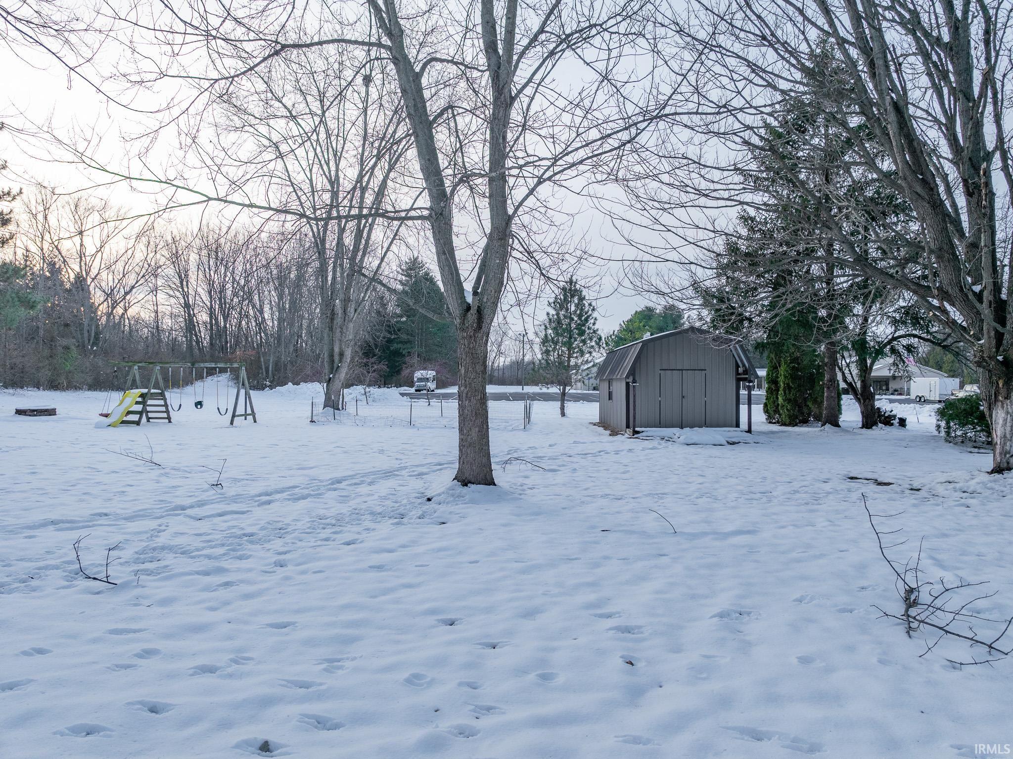 Yard layered in snow featuring a storage unit