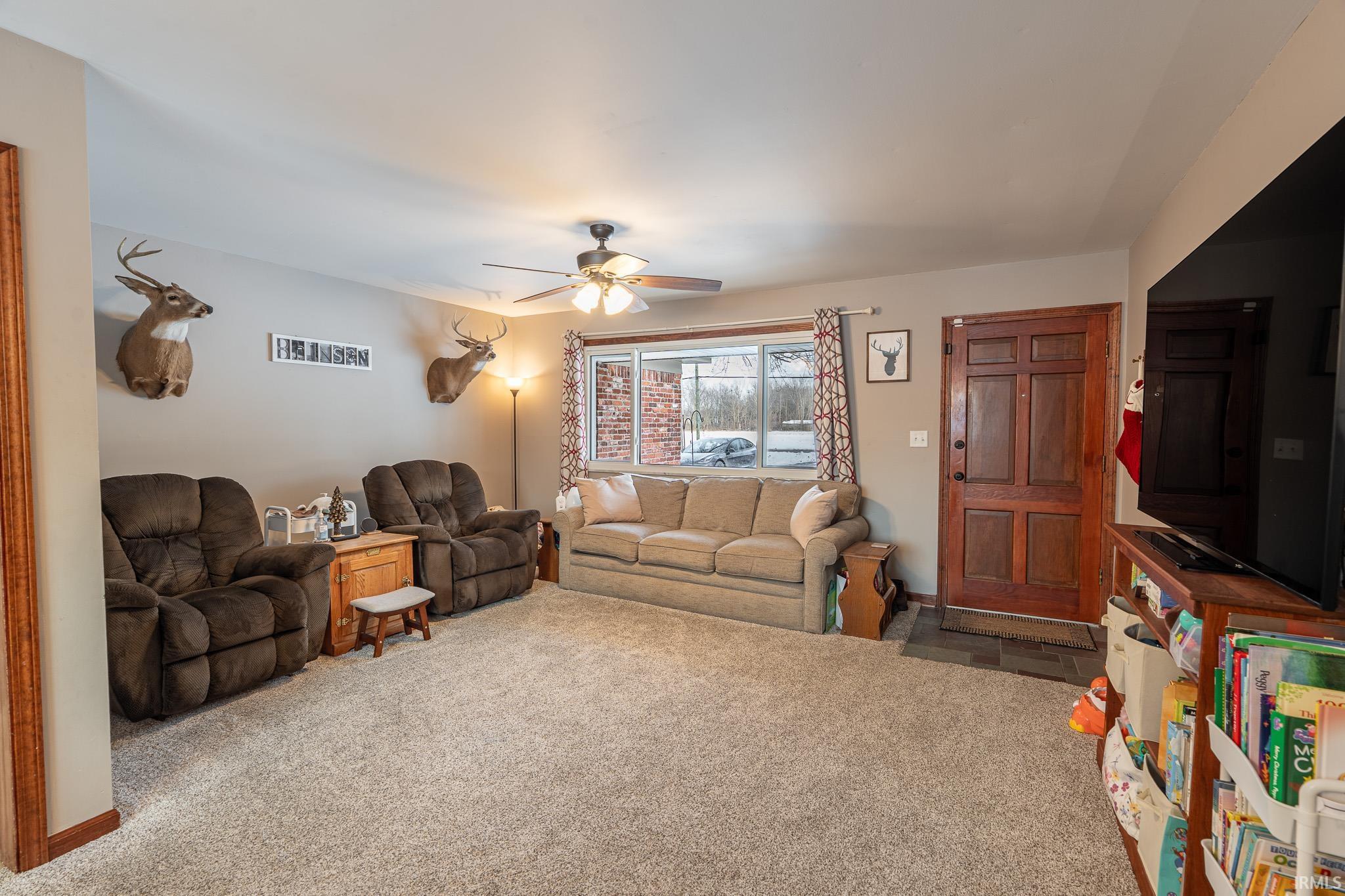 Carpeted living area with ceiling fan