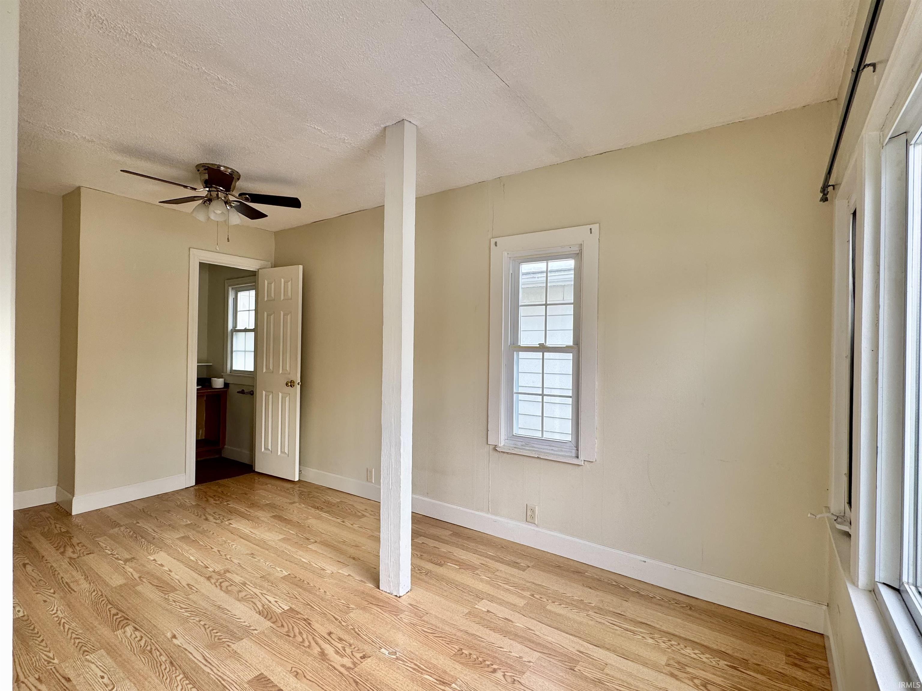 Spare room with light wood finished floors, a textured ceiling, and ceiling fan