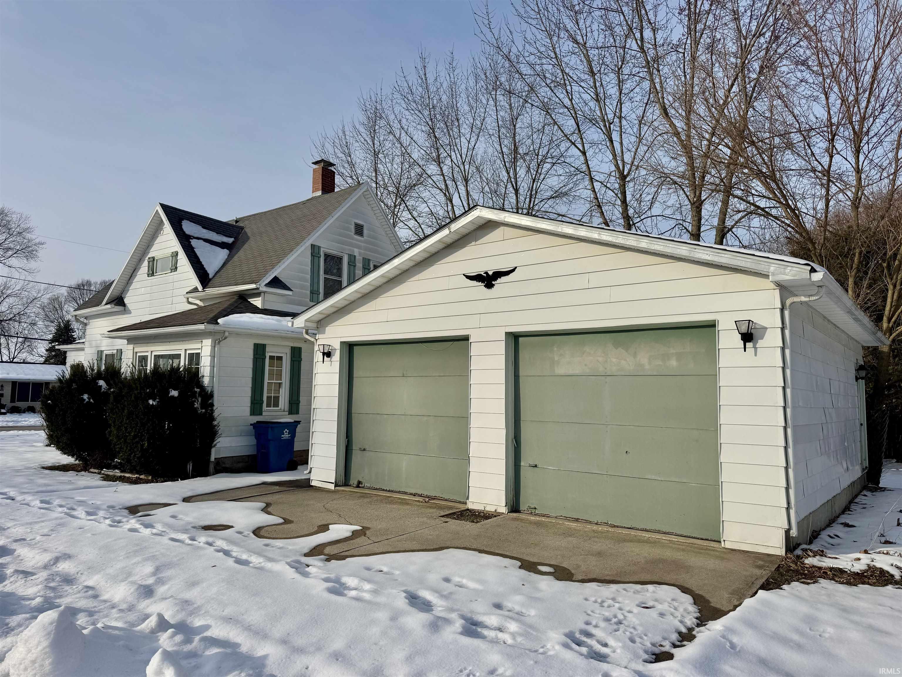 View of front facade featuring a garage and a chimney