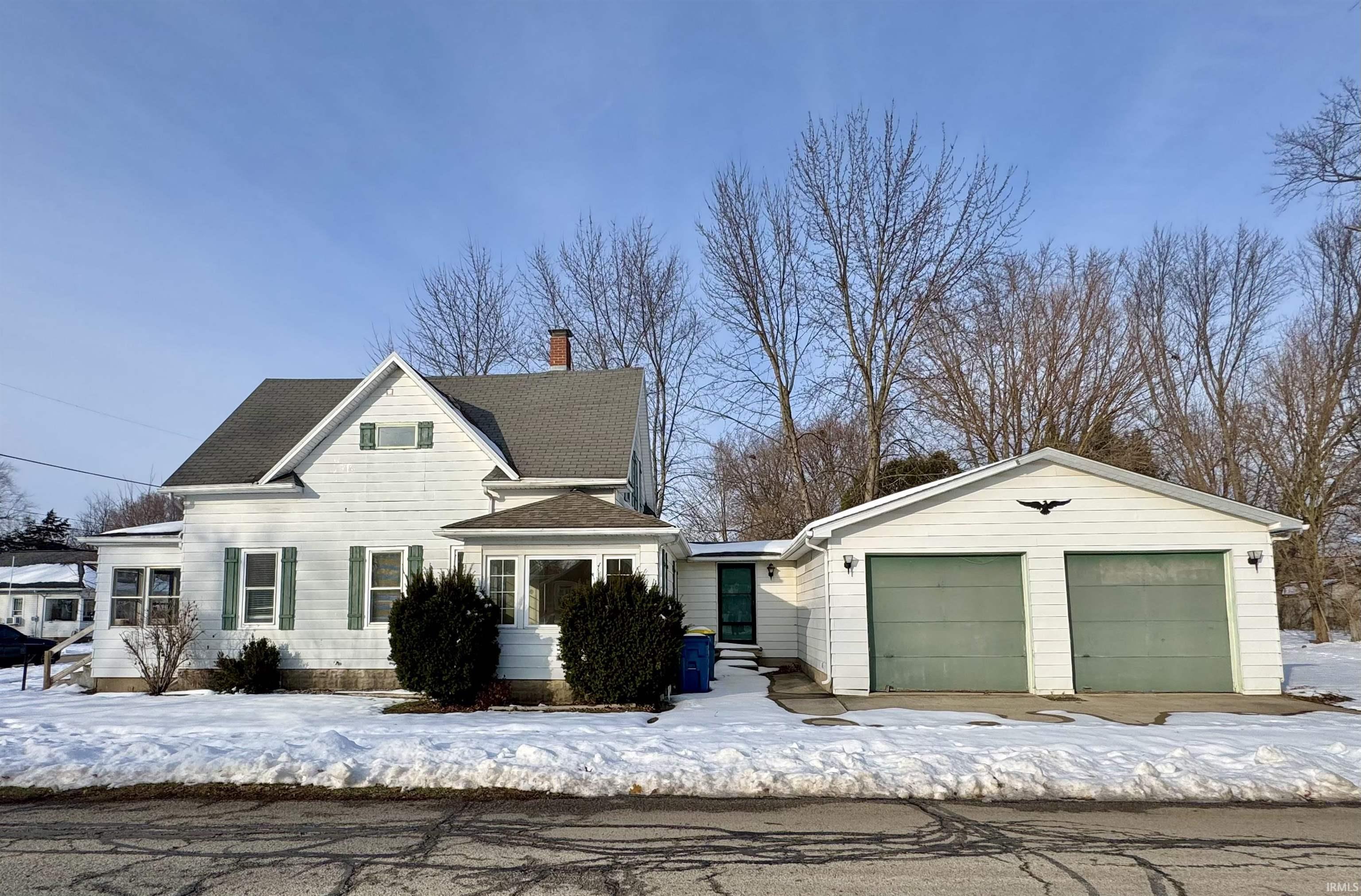 View of front of house with a garage, a chimney, and roof with shingles