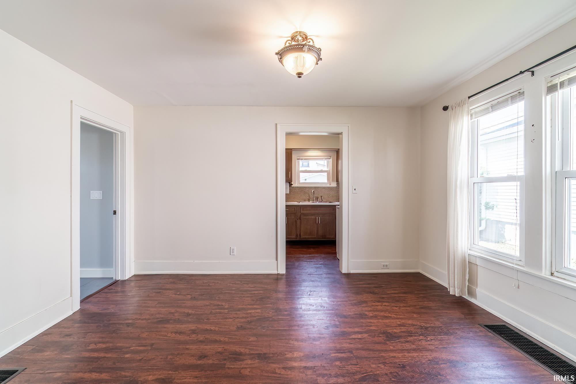 Unfurnished room with dark wood-style floors and baseboards