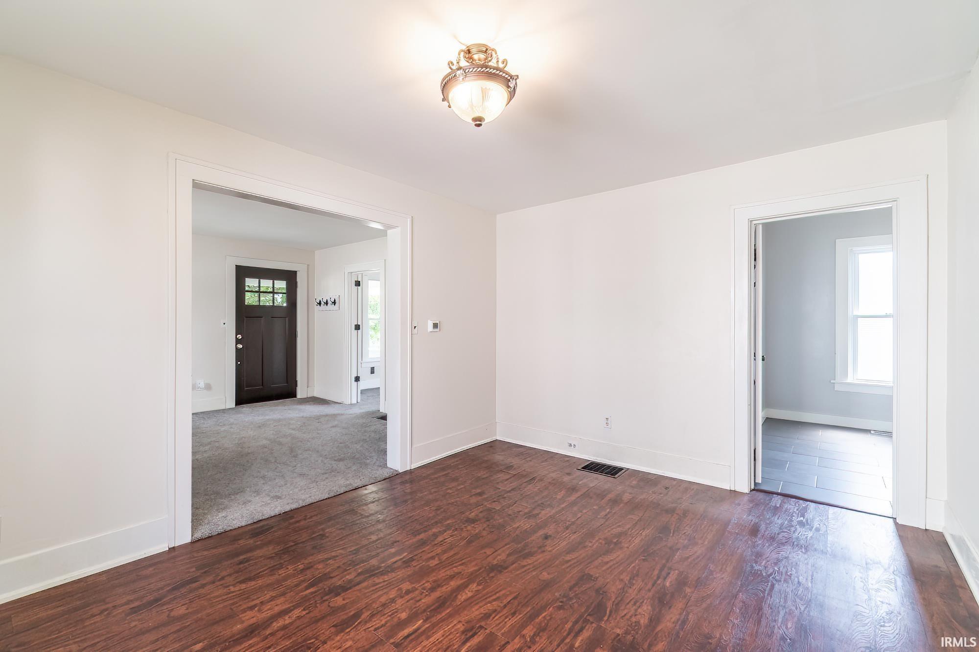 Spare room with dark wood-style floors and baseboards