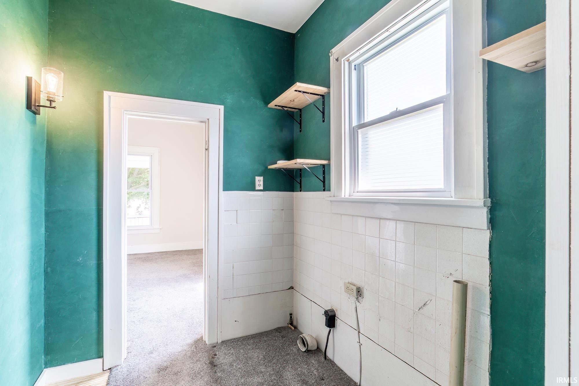 Laundry room featuring carpet and tile walls