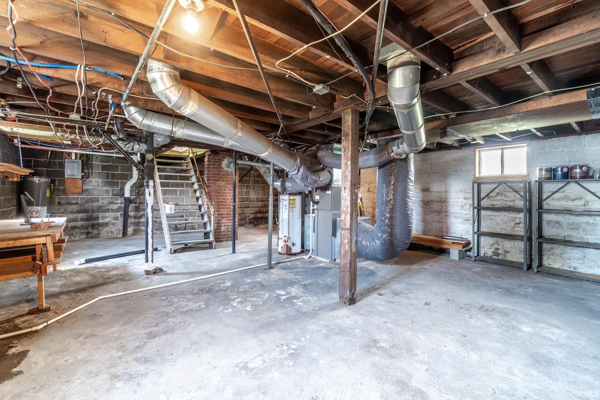 Below grade area featuring stairway and gas water heater