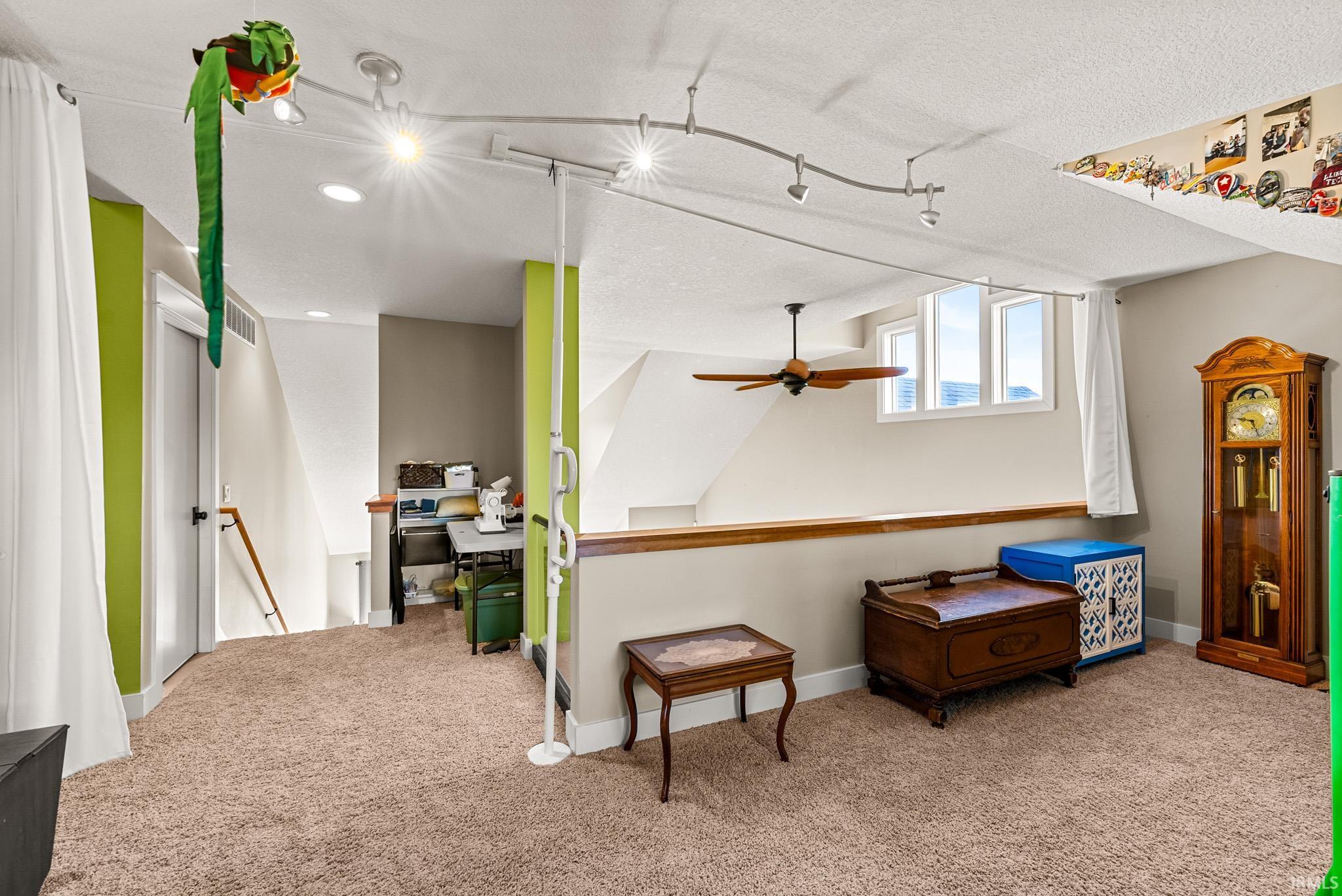 Living area featuring an upstairs landing, carpet flooring, a textured ceiling, ceiling fan, and track lighting