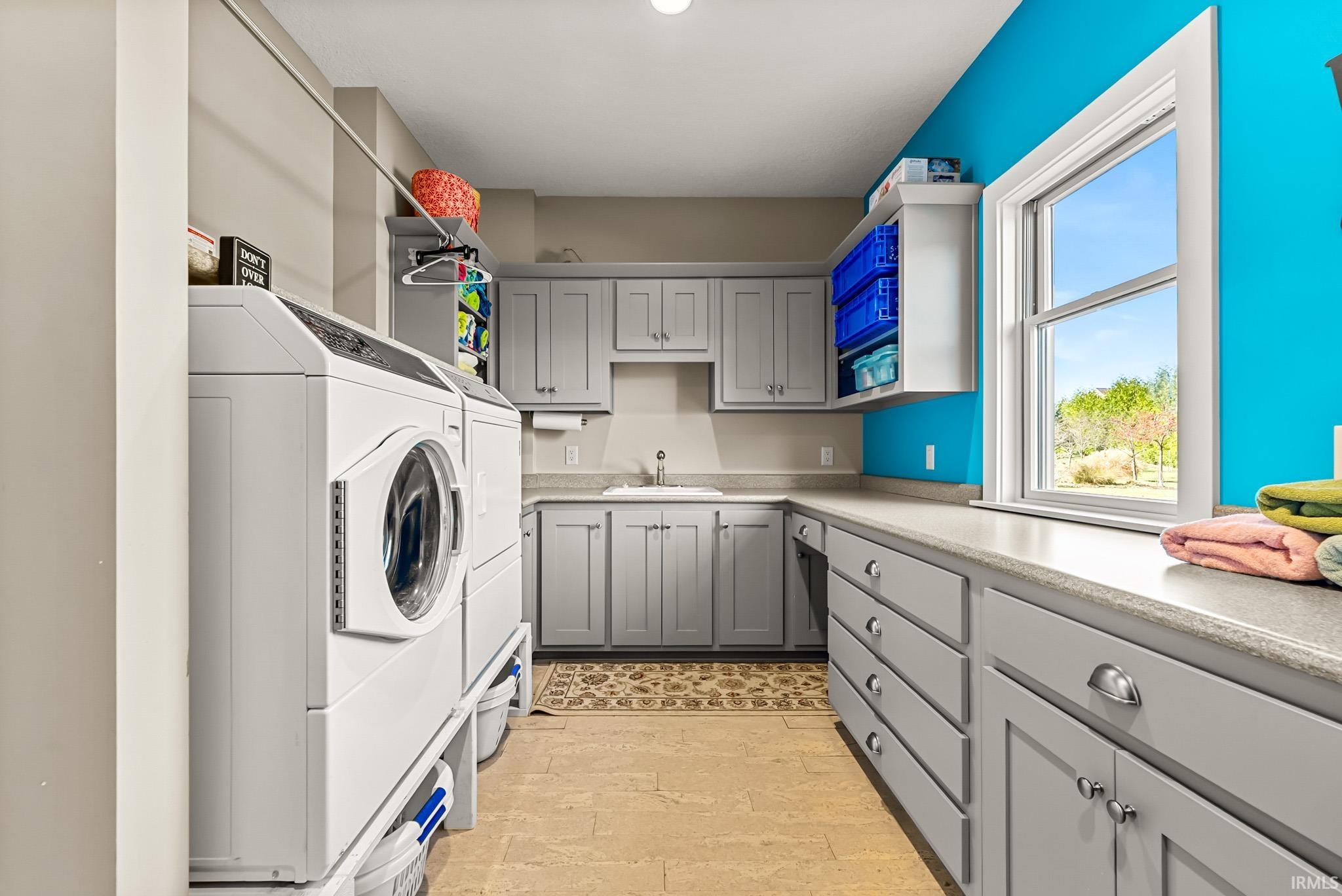 Laundry area featuring light wood finished floors, washer and dryer, and cabinet space