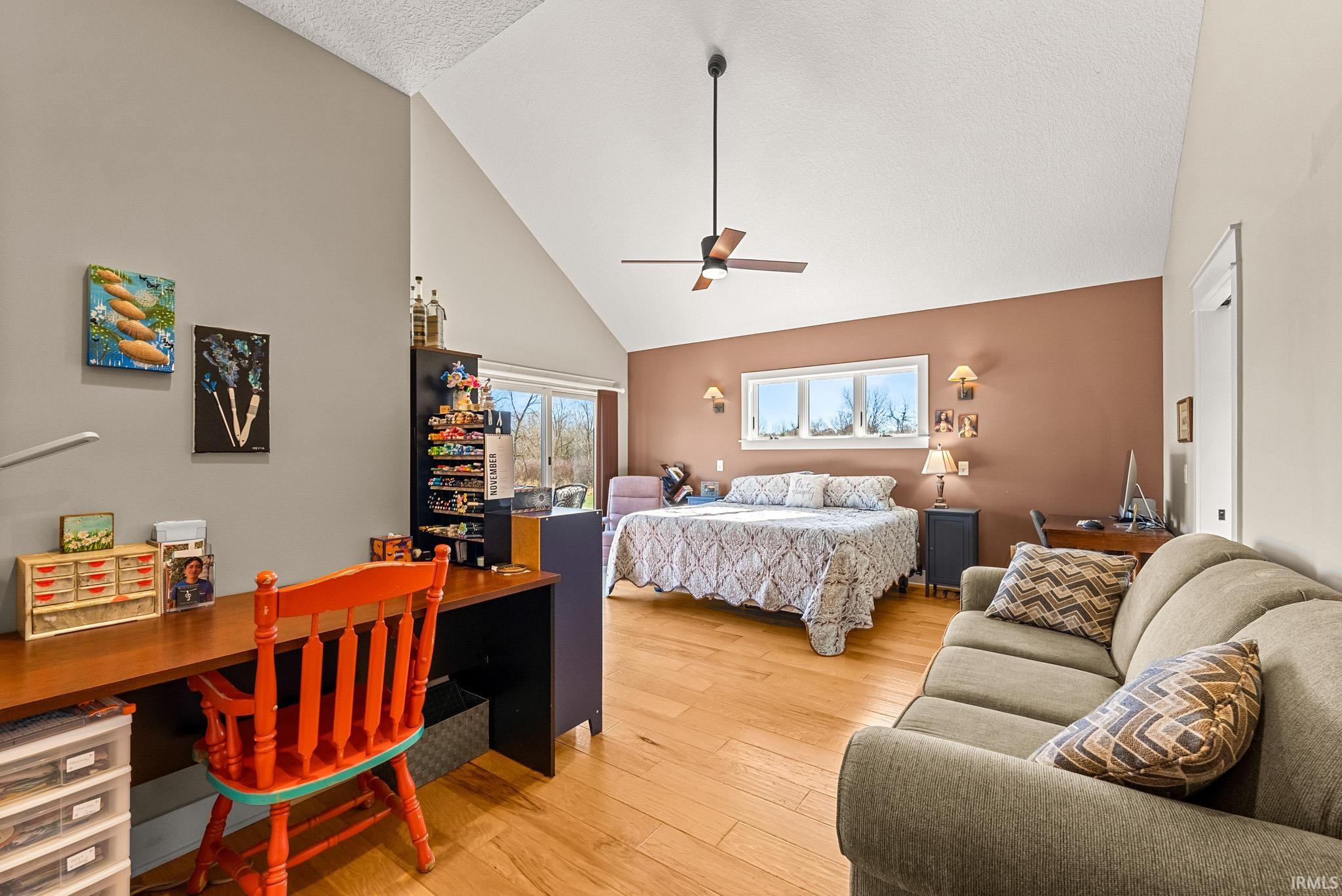 Bedroom featuring high vaulted ceiling, light wood-style flooring, a textured ceiling, ceiling fan, and a desk