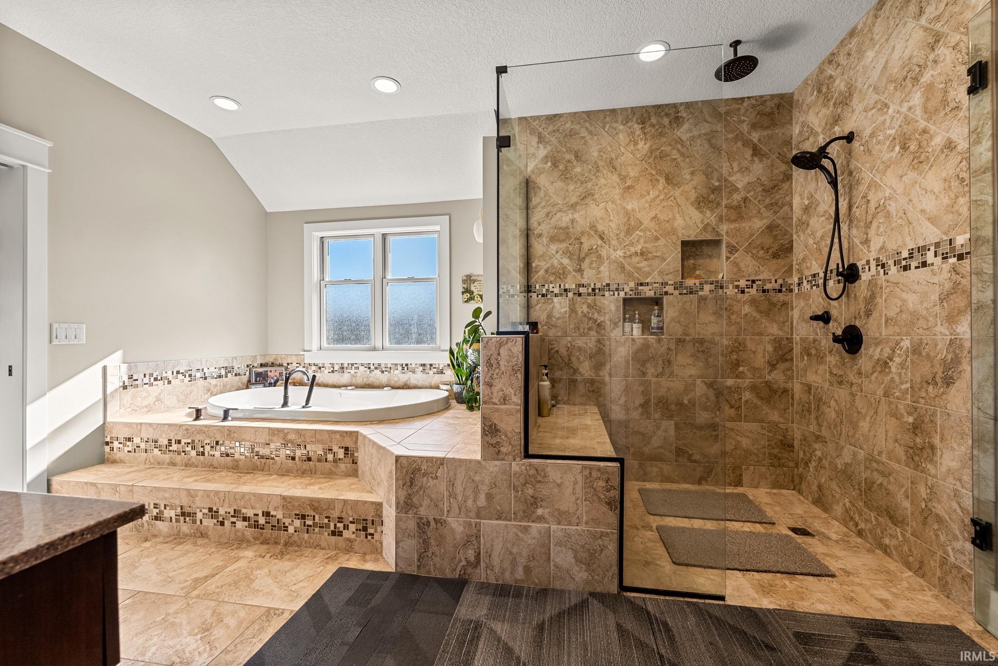 Bathroom featuring a garden tub, tile patterned flooring, a stall shower, lofted ceiling, and recessed lighting