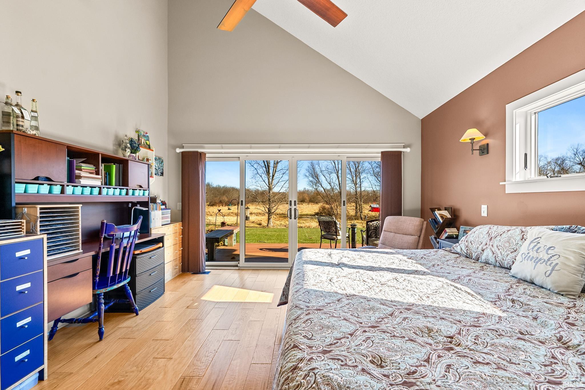 Bedroom featuring access to outside, high vaulted ceiling, light wood-style flooring, a ceiling fan, and an office area