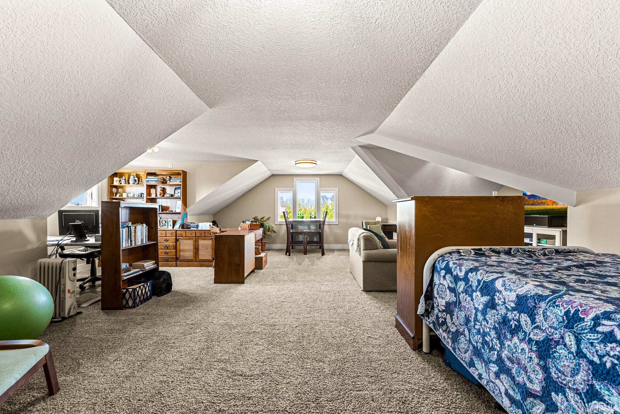 Bedroom with carpet flooring, a textured ceiling, and lofted ceiling
