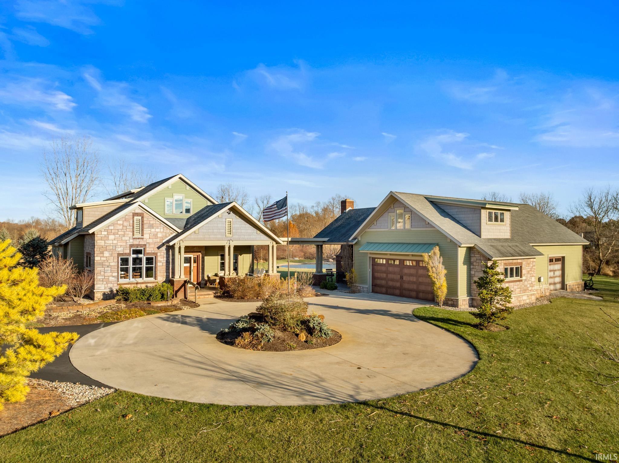 Craftsman-style home featuring stone siding, a front lawn, curved driveway, a porch, and a chimney