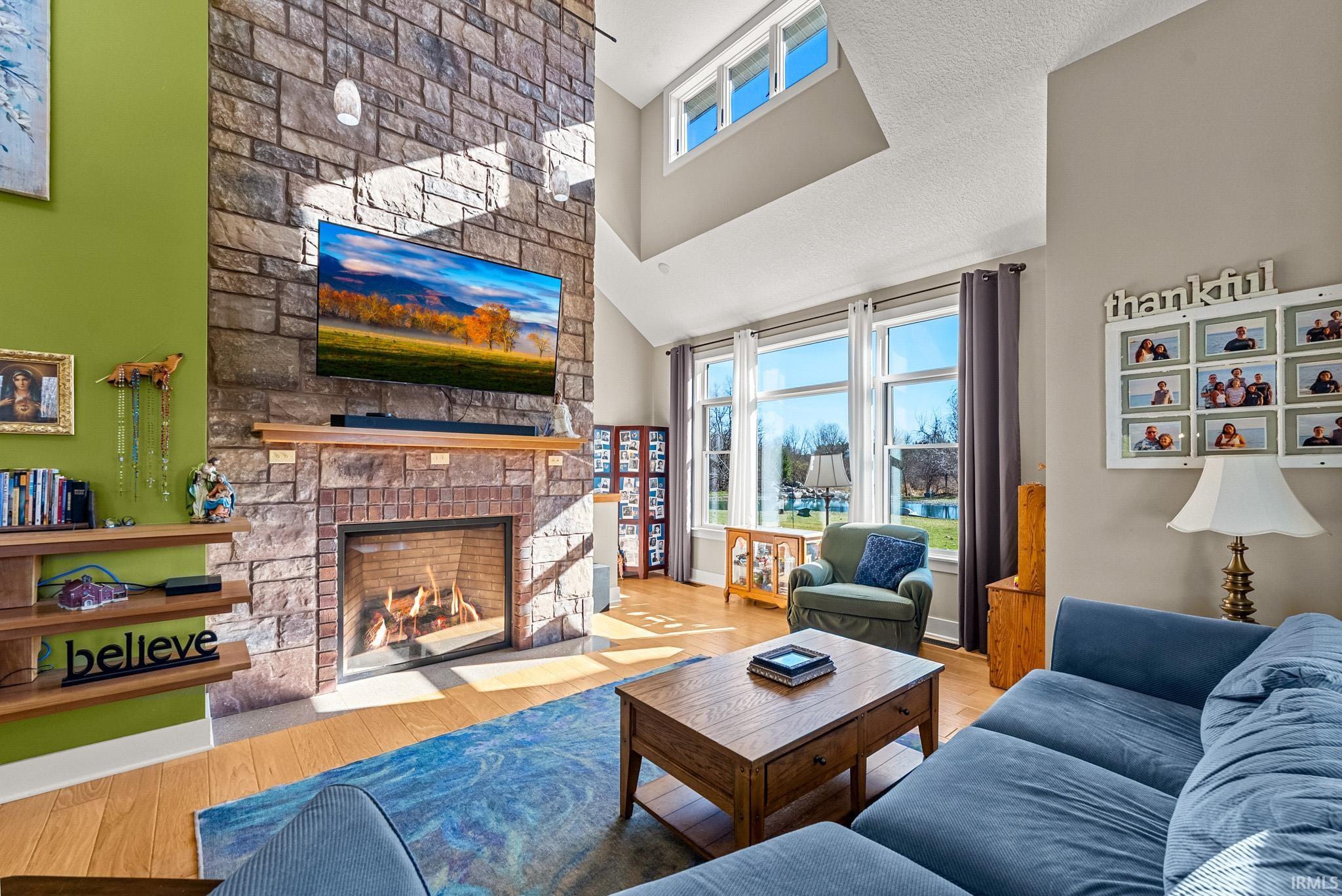 Living room featuring a fireplace, a towering ceiling, and wood finished floors