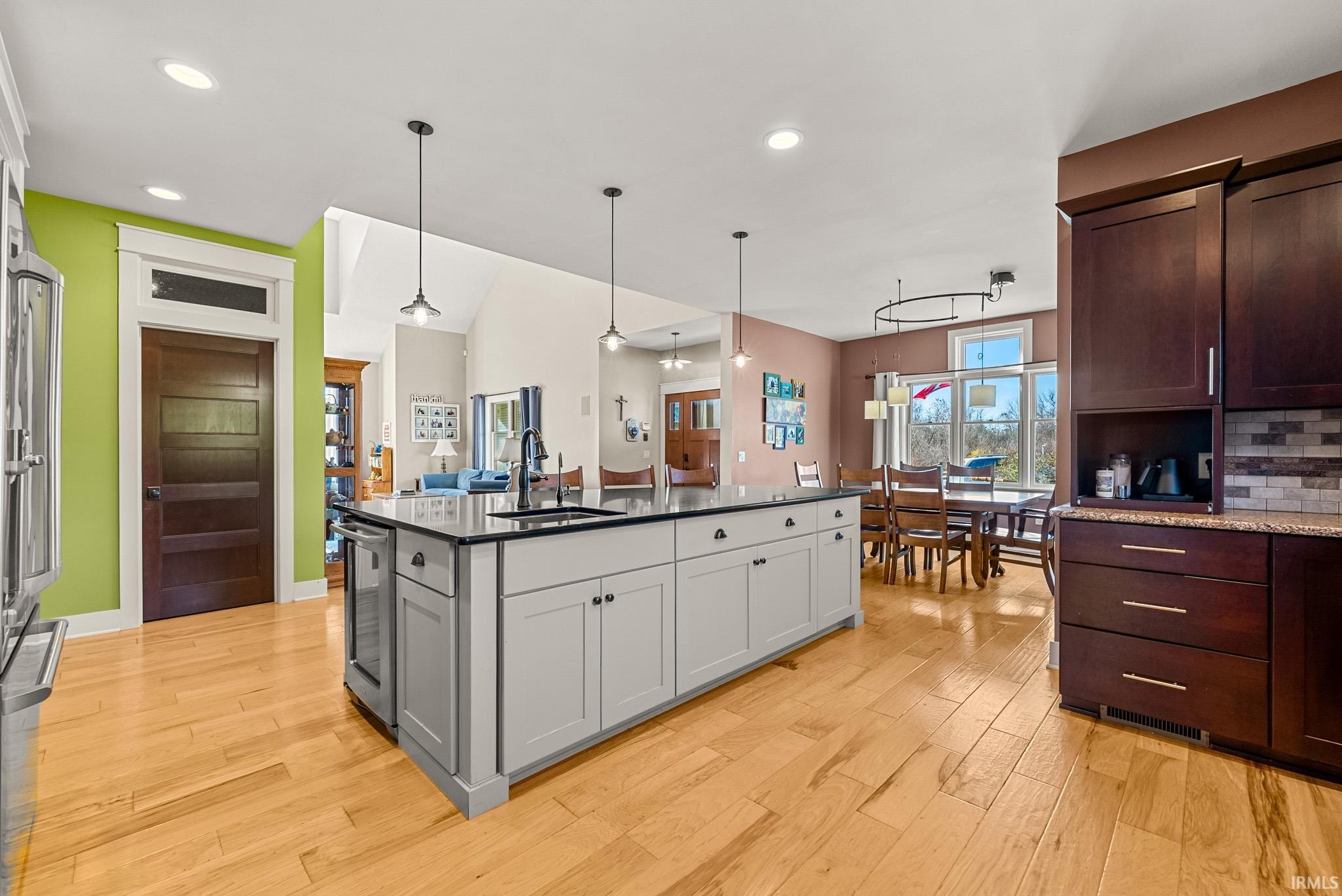 Kitchen with gray cabinets, pendant lighting, light wood-style flooring, backsplash, and dark stone countertops