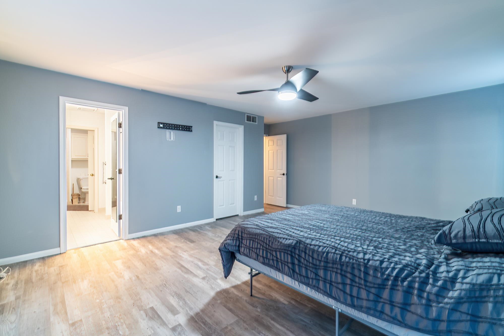 Bedroom featuring wood finished floors, ceiling fan, and ensuite bathroom