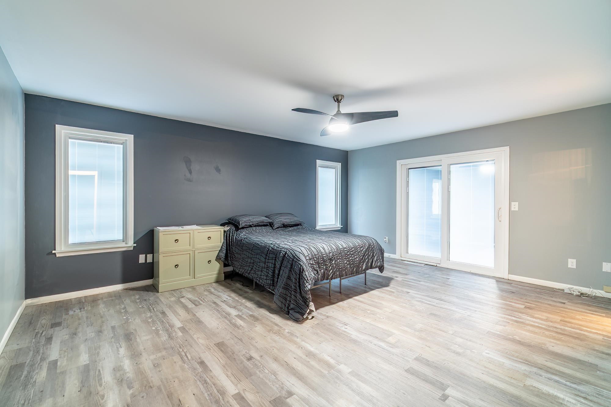 Bedroom featuring light wood-style flooring, ceiling fan, and multiple windows