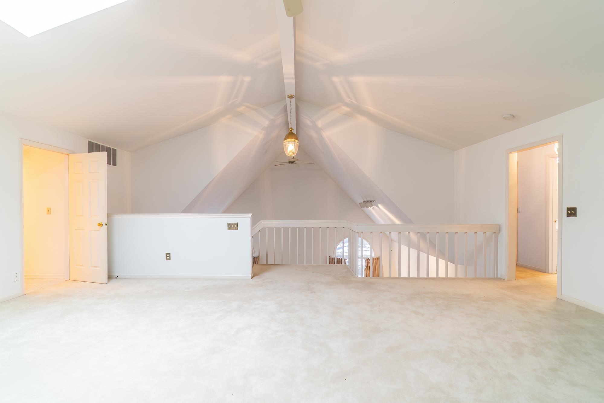 Bonus room with vaulted ceiling and light colored carpet