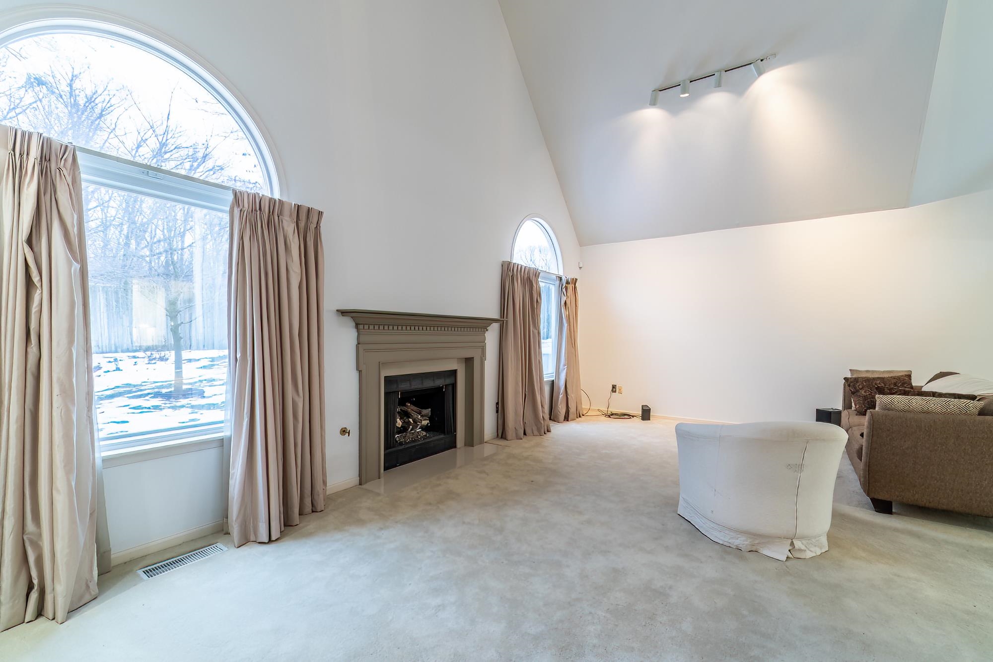 Living area featuring high vaulted ceiling, carpet floors, a fireplace, and rail lighting