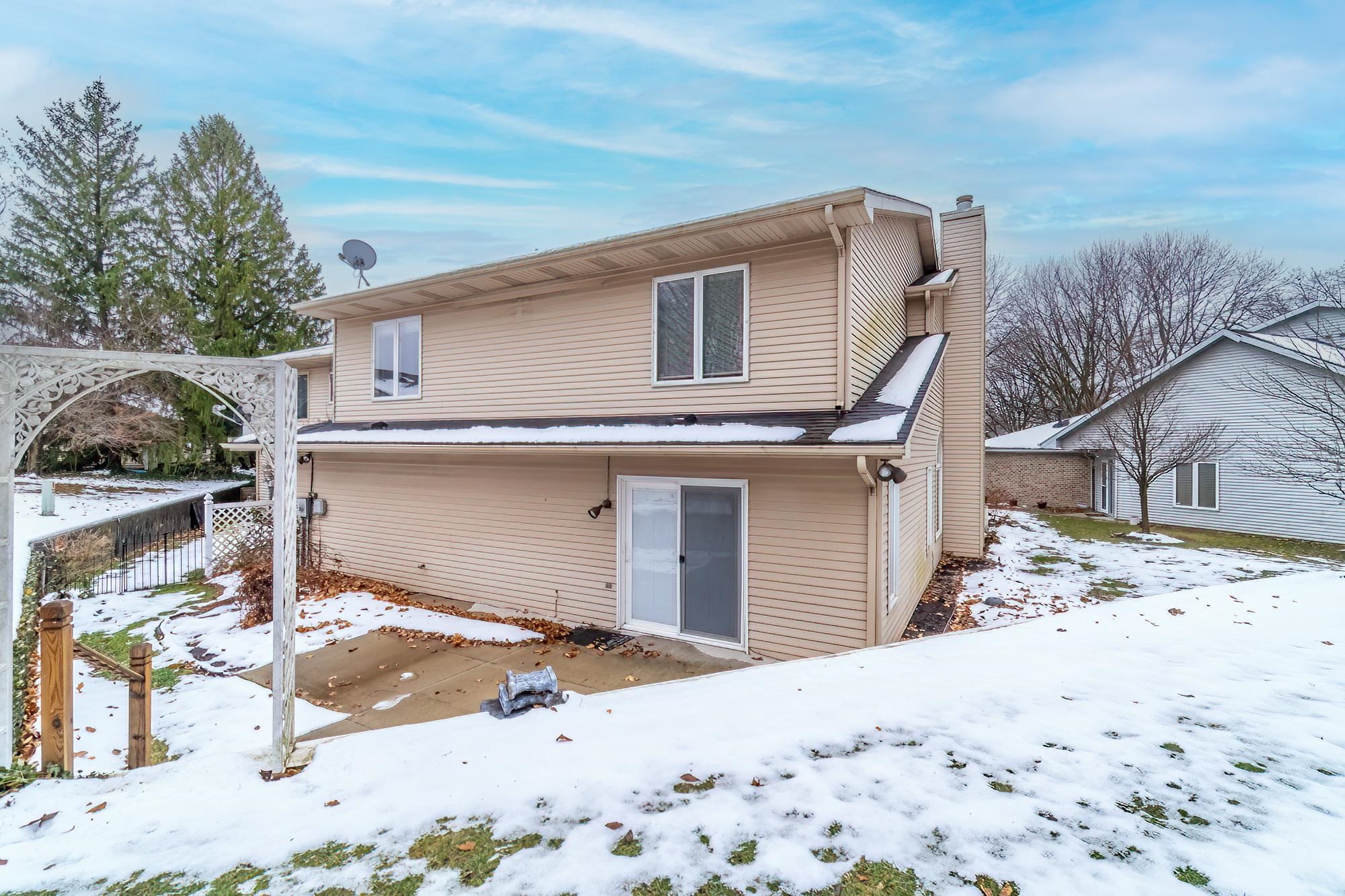 Snow covered rear of property featuring a chimney and a patio