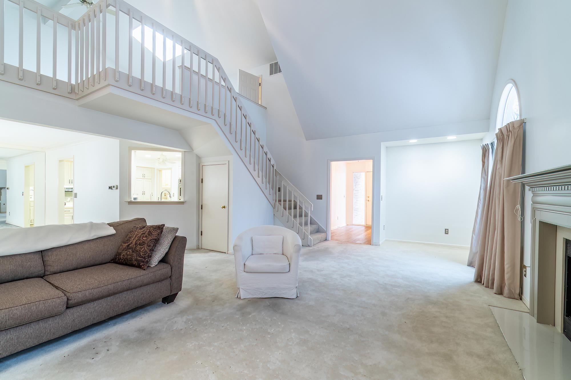 Living room featuring a high ceiling, stairs, and a fireplace