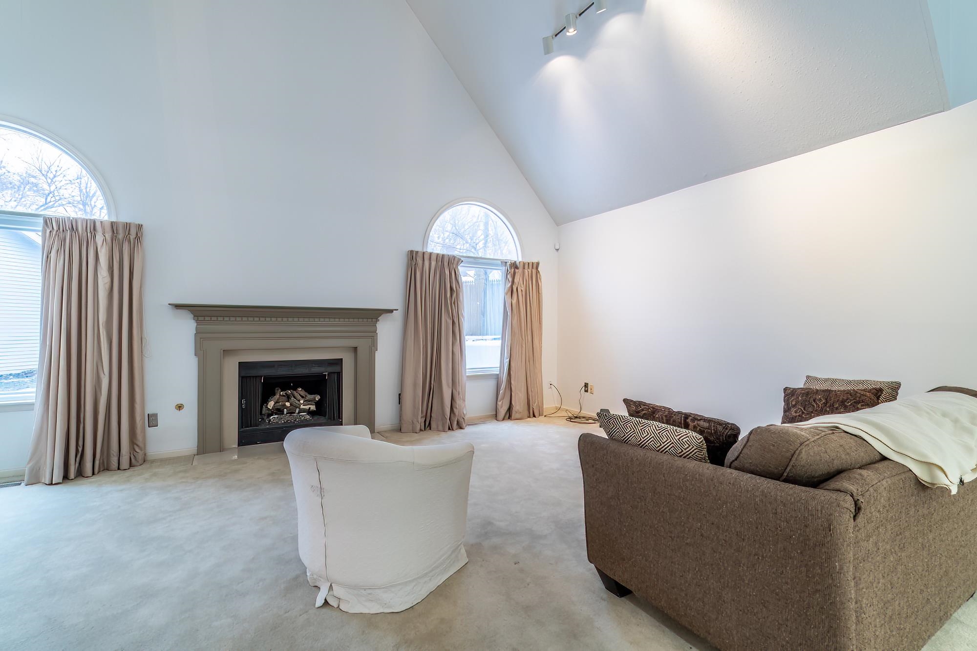 Living room featuring high vaulted ceiling, a fireplace, and carpet