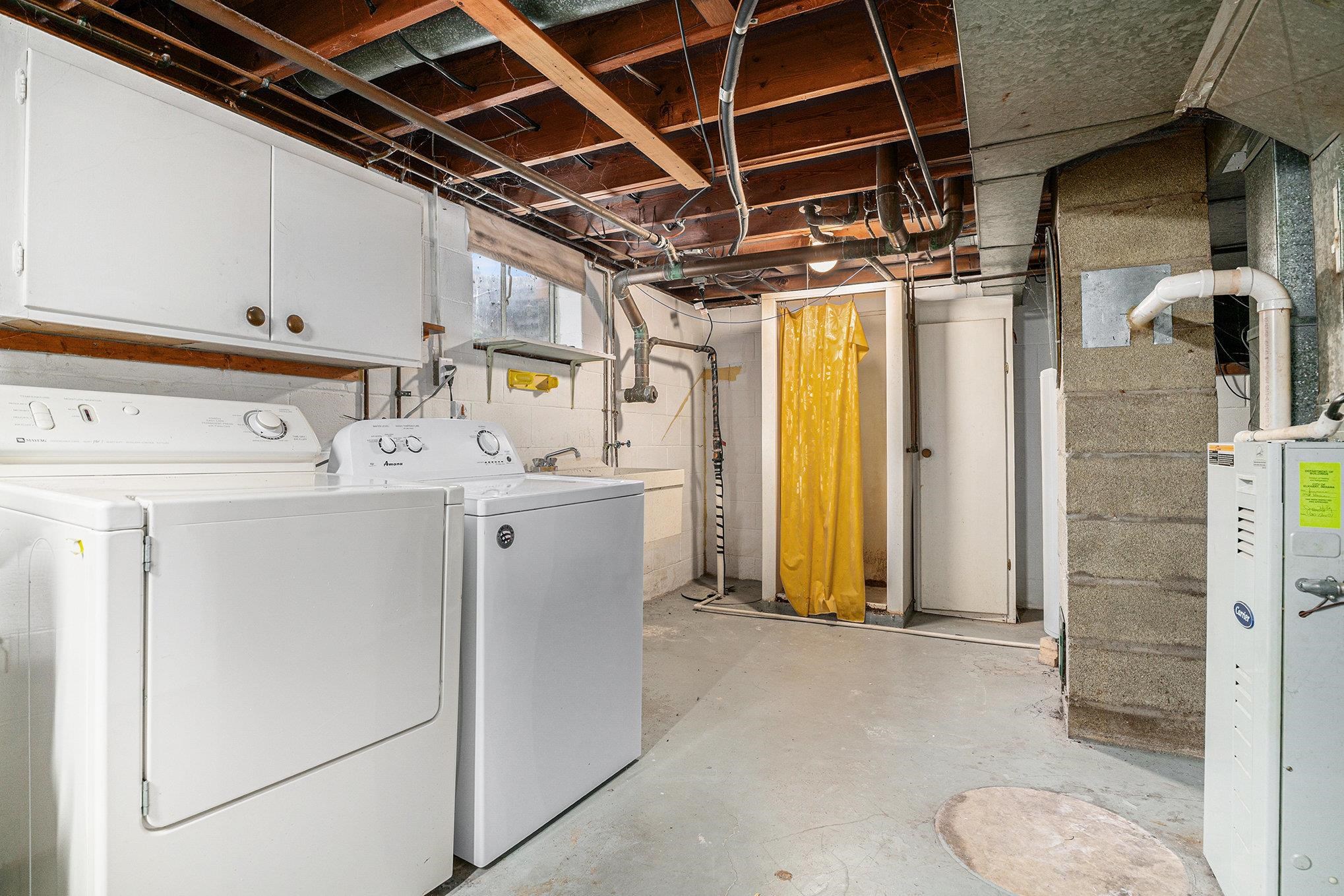 Laundry area with unfinished concrete floors and washing machine and clothes dryer