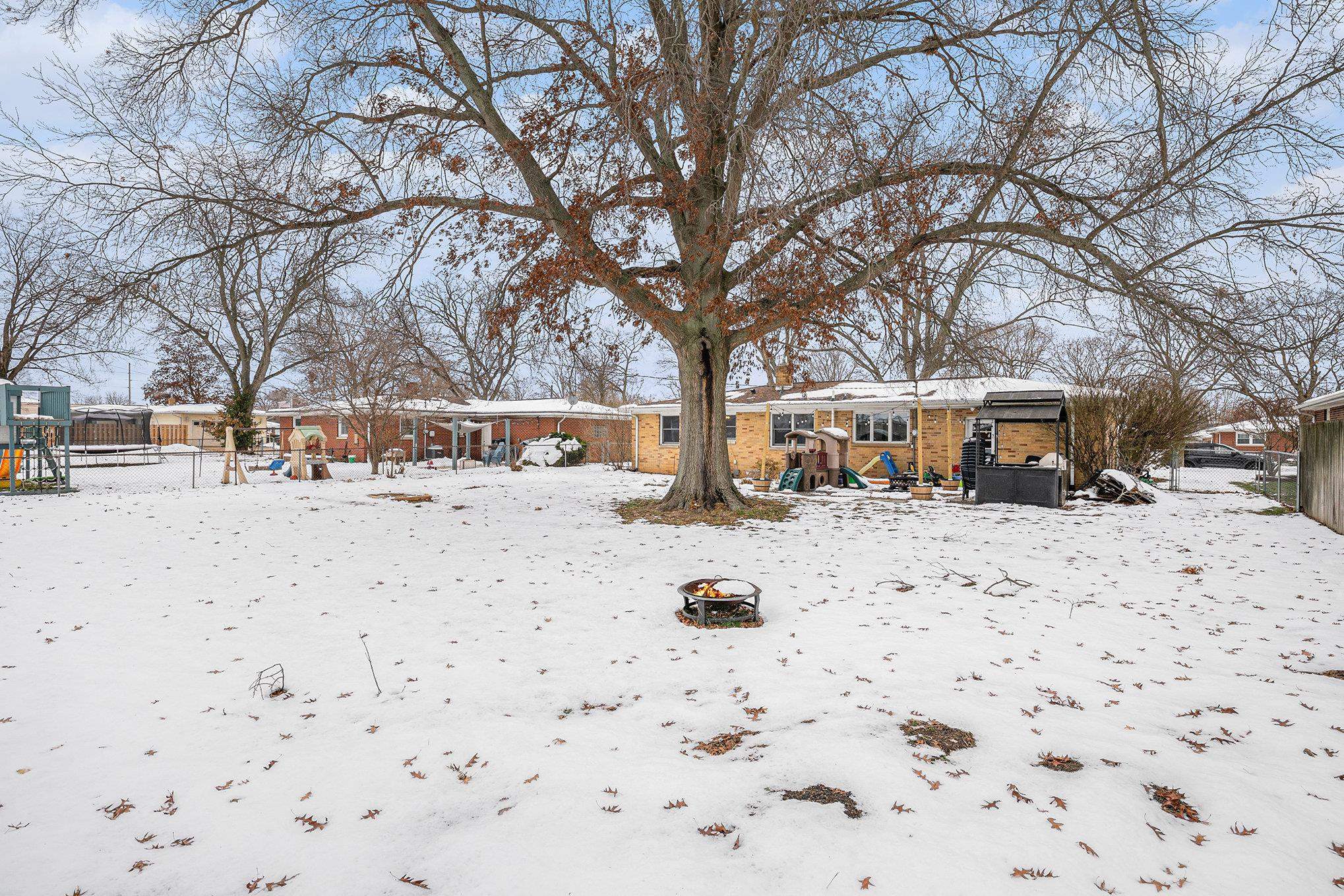Yard layered in snow featuring a patio