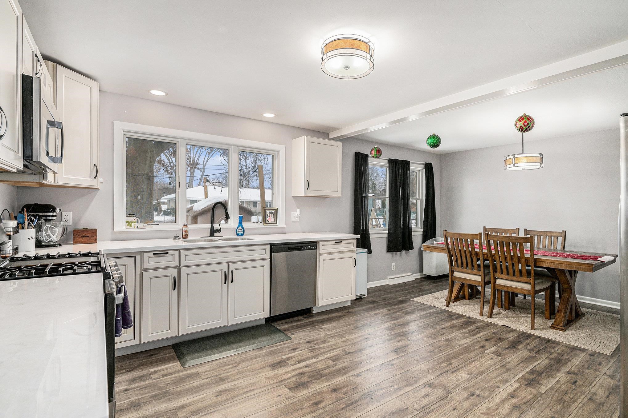 Kitchen with stainless steel appliances, decorative light fixtures, white cabinets, light wood-style floors, and recessed lighting