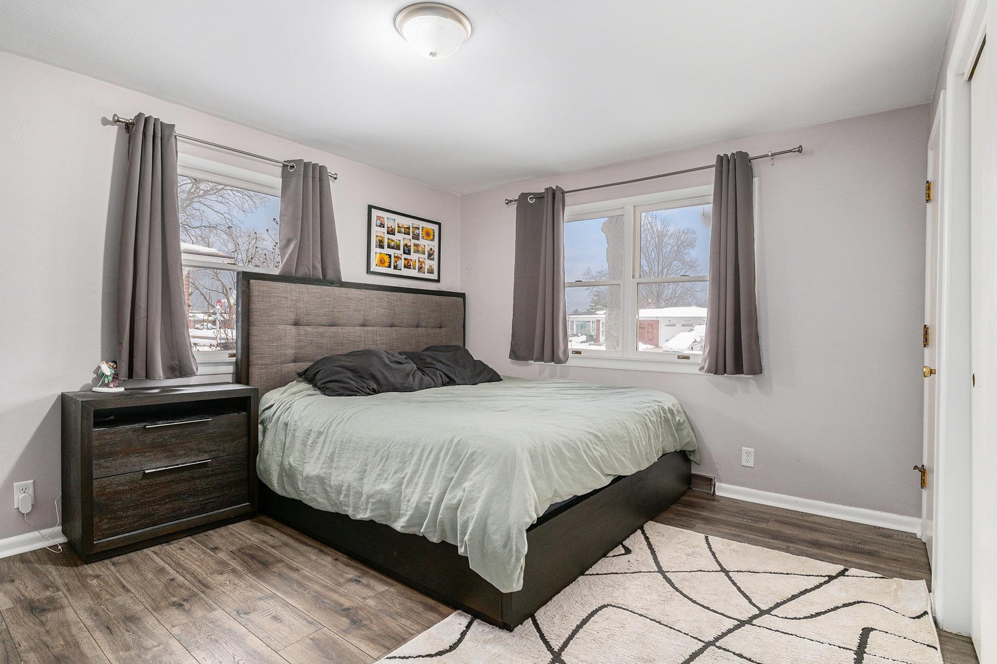 Bedroom with wood finished floors and multiple windows
